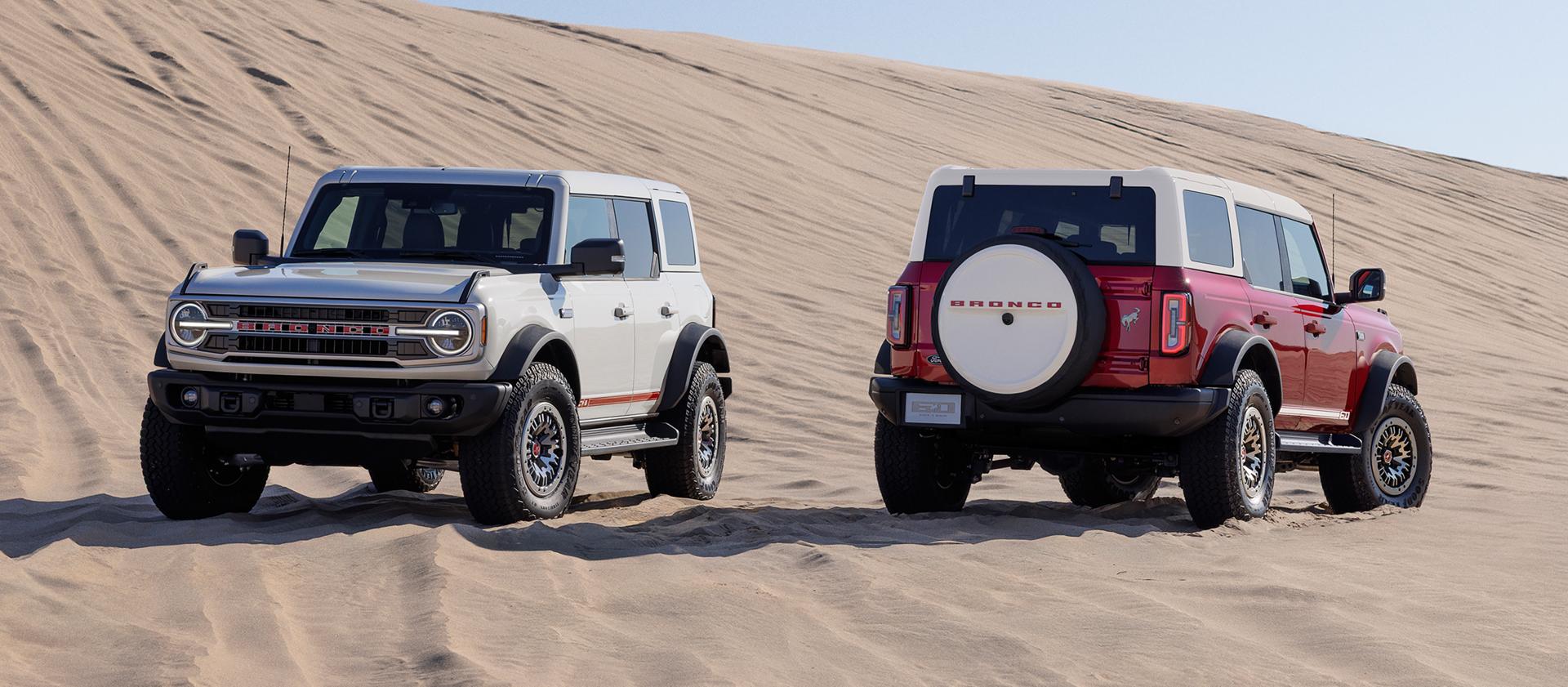 Deux VUS Ford Bronco Outer Banks® 2026 avec l’ensemble 60e anniversaire en option stationnés sur une étendue de sable.