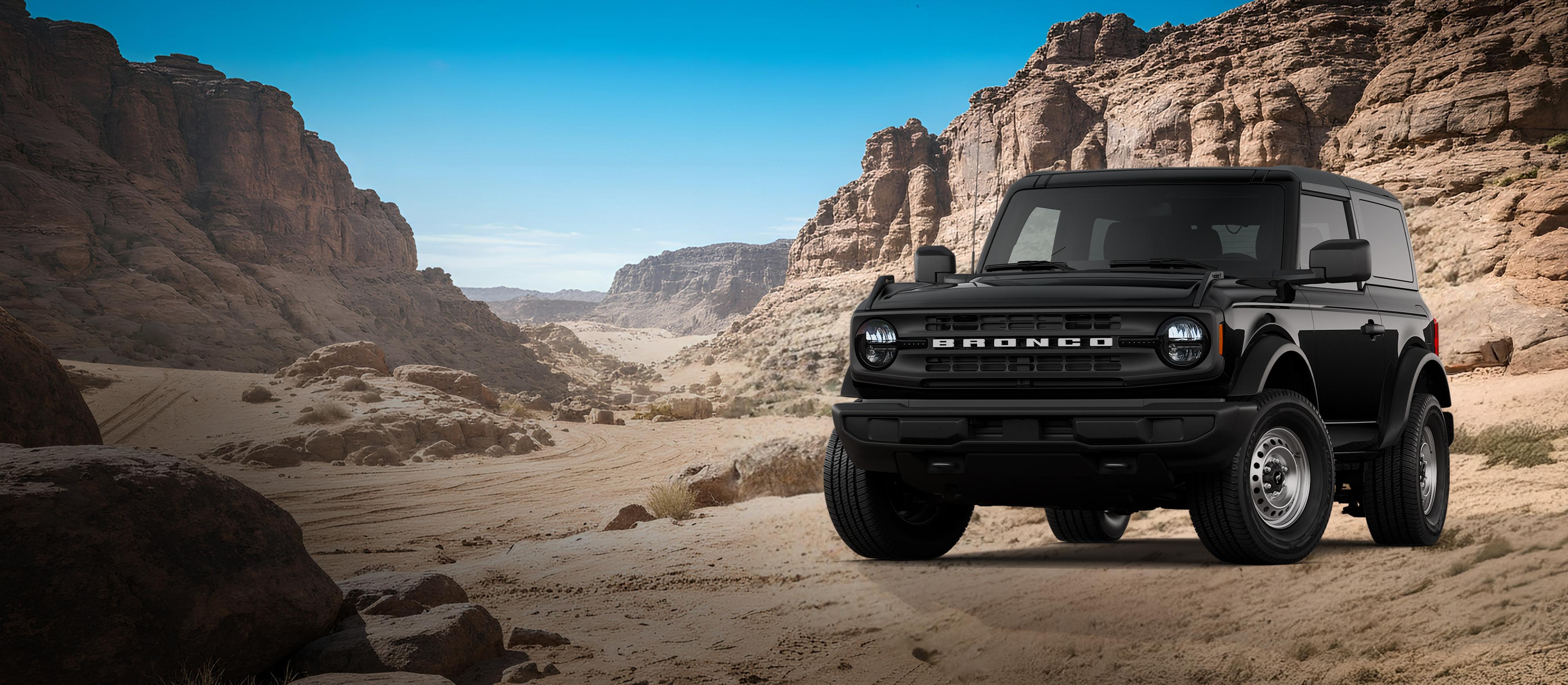 Un modèle de base du Ford Bronco® 2026 montré en noir ombre stationné sur une étendue rocheuse