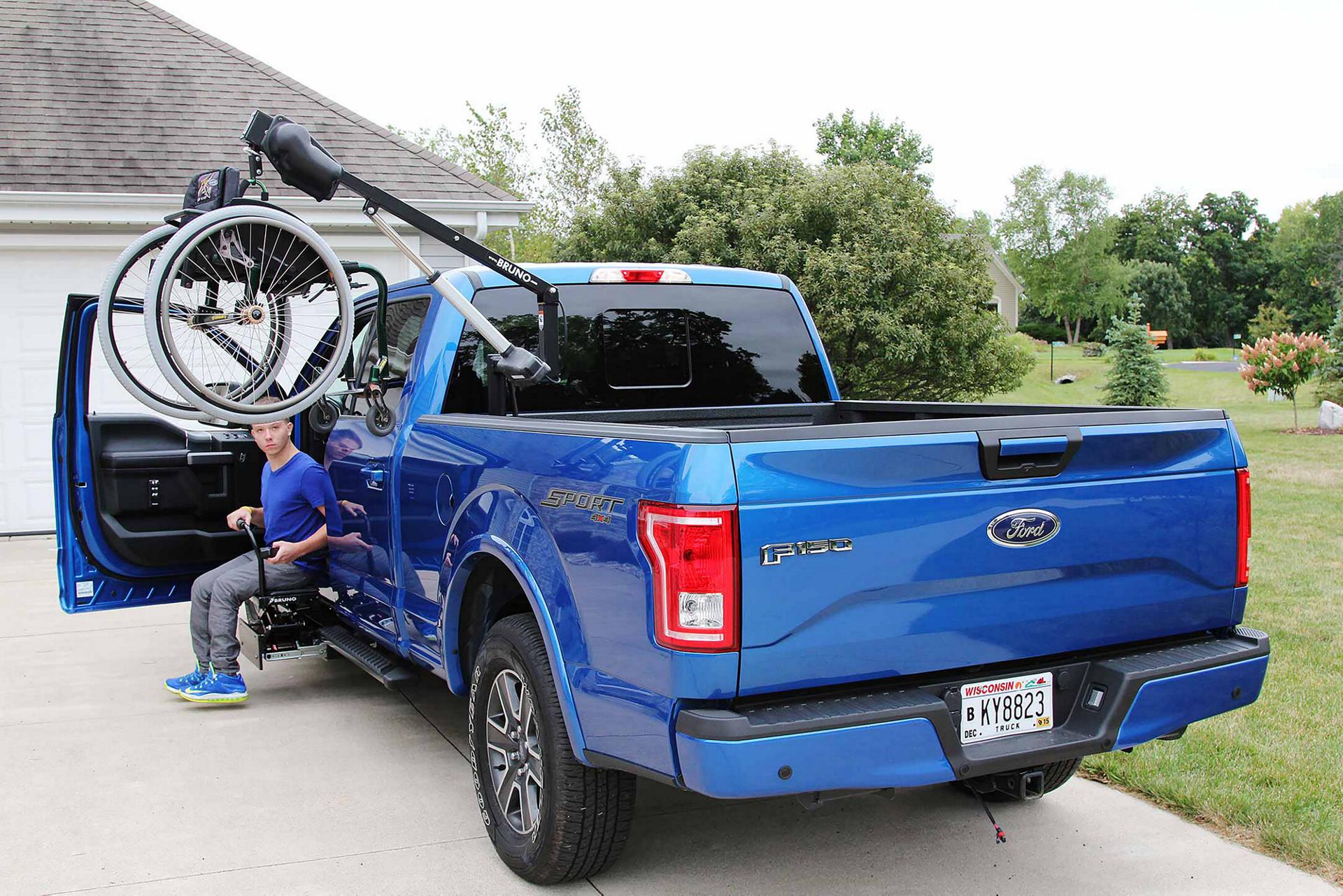 Un F-150 bleu avec un palan de fauteuil roulant dans la caisse