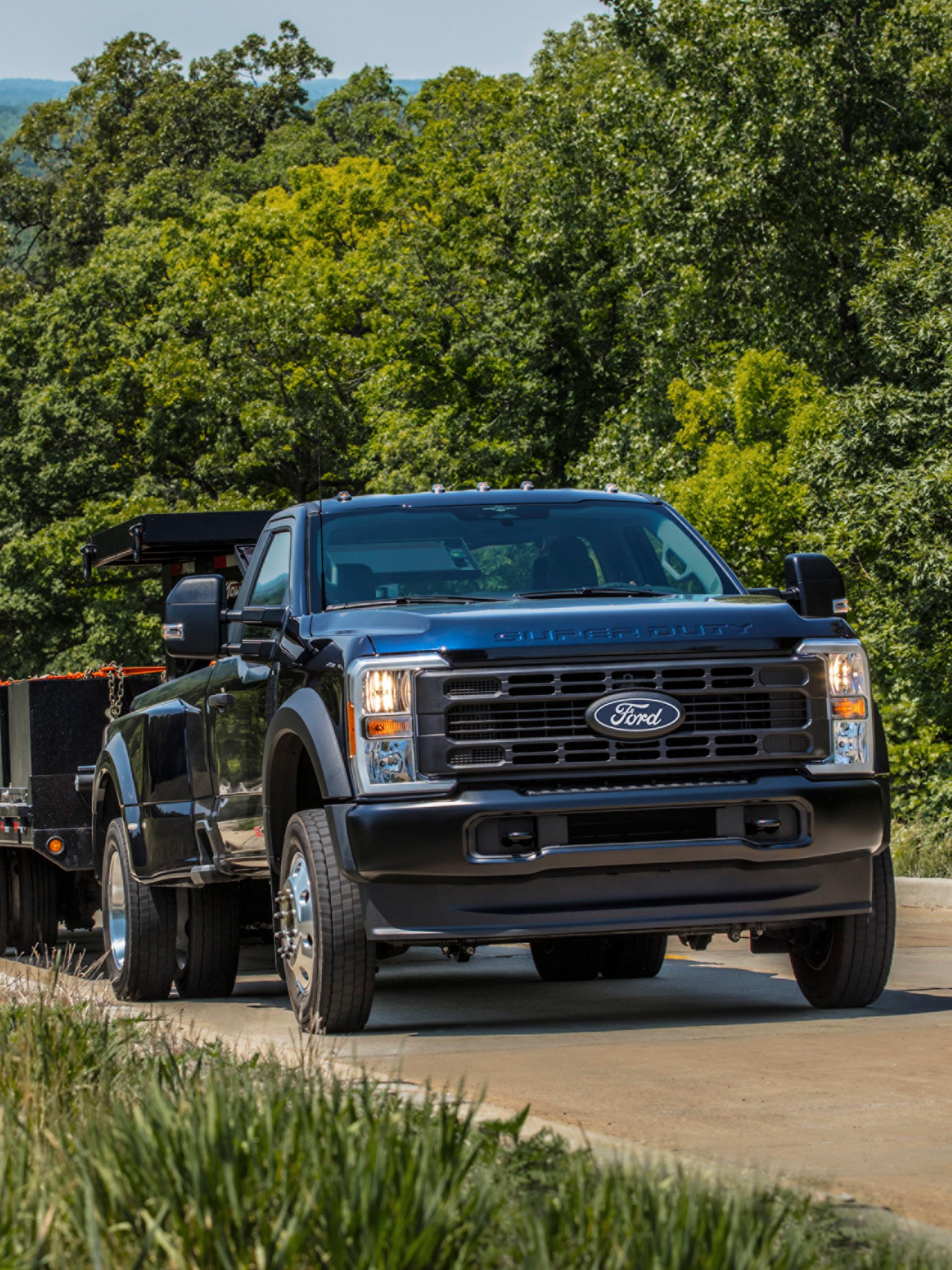 La camionnette Ford Super Duty® 2027 tirant une grande remorque à plateau le long d’une colline pavée