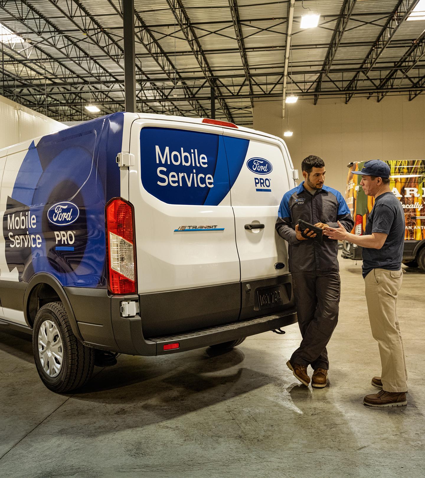 Un technicien du service d’entretien mobile Ford discute avec un propriétaire de parc automobile.