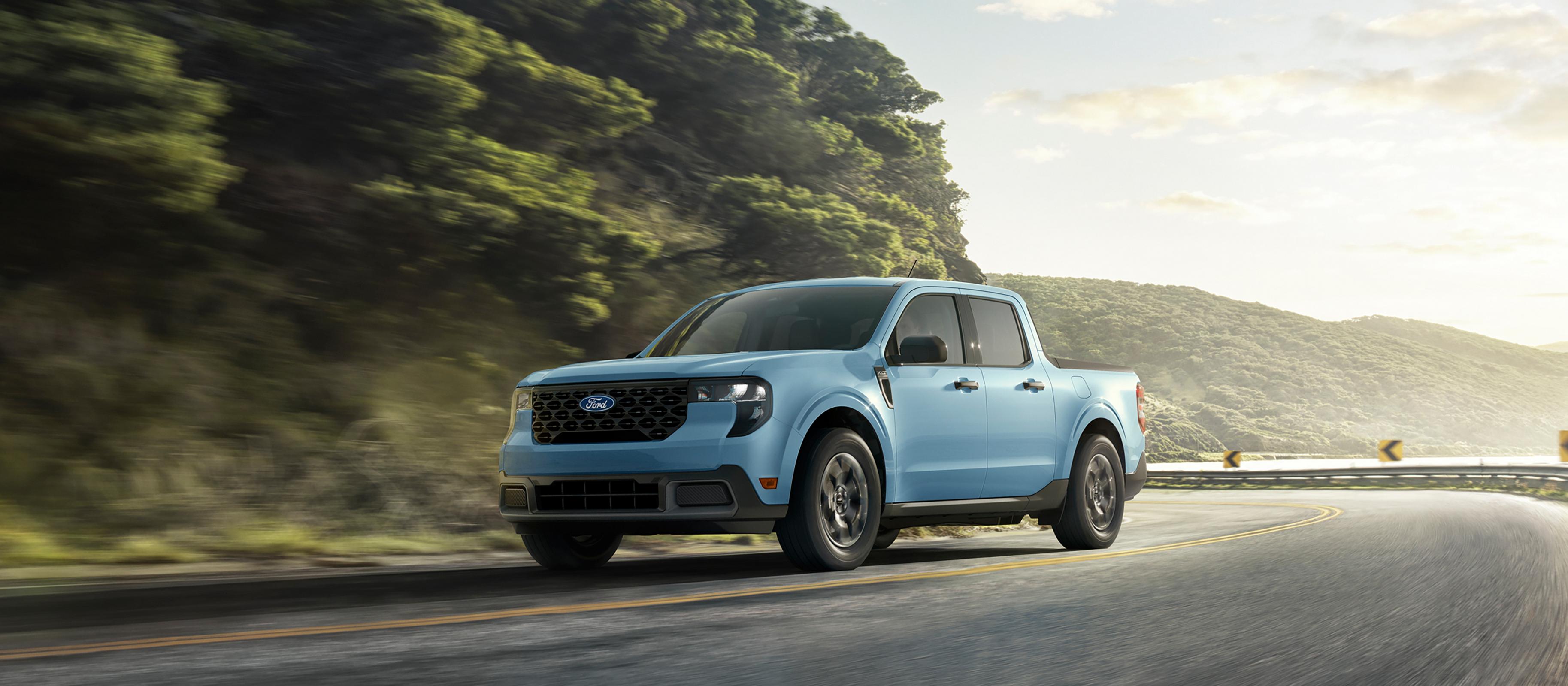 Une camionnette Ford Maverick® 2026 circulant sur une route sinueuse près d’un lac de montagne