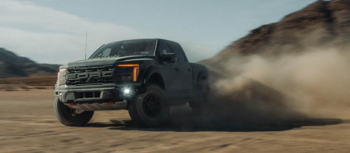 Un camion Ford F-150® Raptor® R™ 2026 conduit dans le désert et soulève des nuages ​​de sable