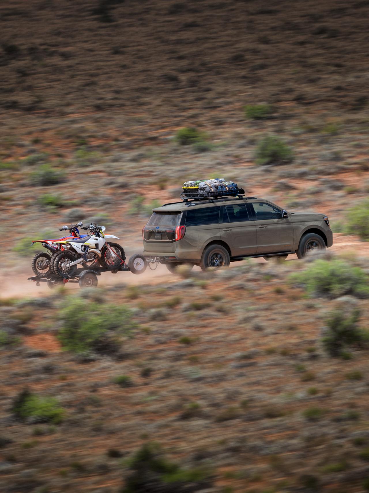 Le VUS Ford Expedition® Tremor® 2027 remorquant une remorque de moto tout-terrain dans le désert