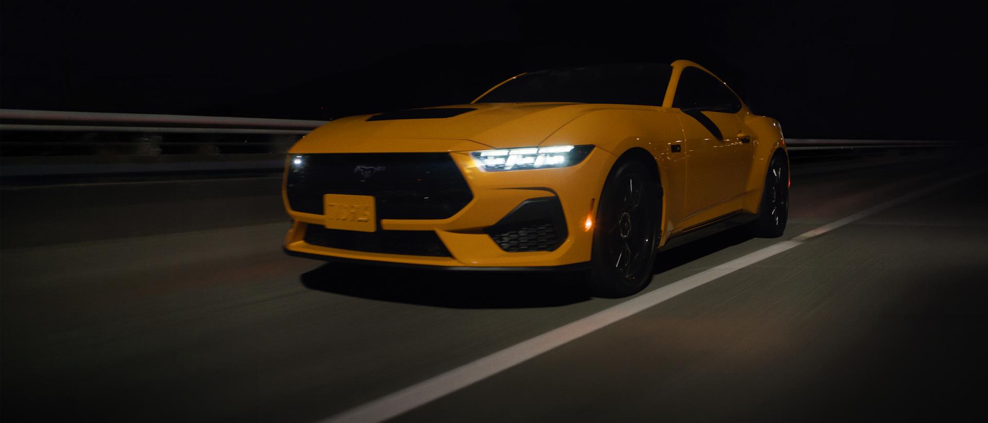 Une Mustang roulant de nuit sur une autoroute.
