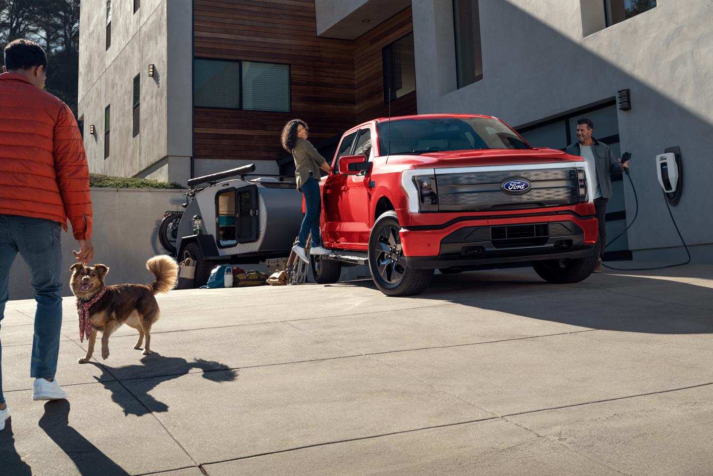 Un F-150 Lightning stationné dans une allée à côté d'une station de recharge Ford Pro.