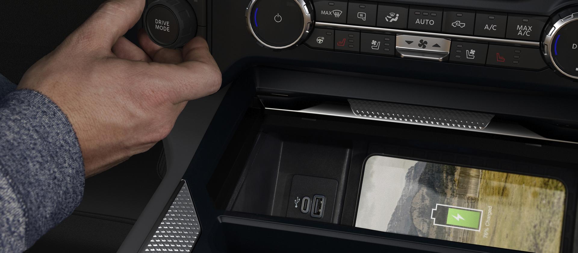 Main d’une personne réglant le bouton du mode de conduite du Ford Super Duty® 2027 tandis qu’un téléphone se recharge sur le socle de recharge sans fil.