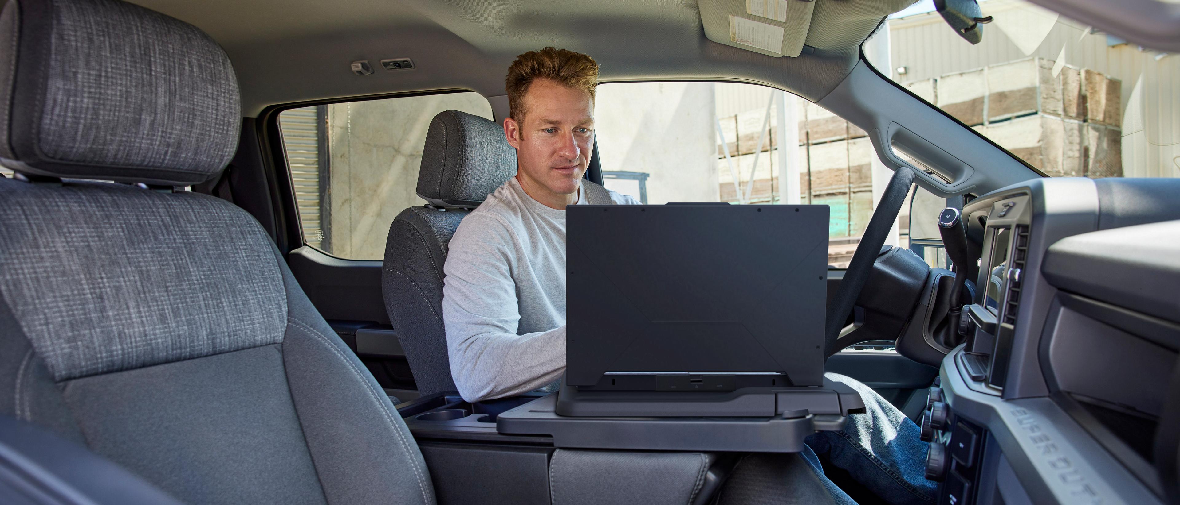 Une personne travaillant sur un ordinateur portable utilisant la surface de travail intérieure à l’intérieur de l’habitacle de son camion Ford Super Duty® 2026