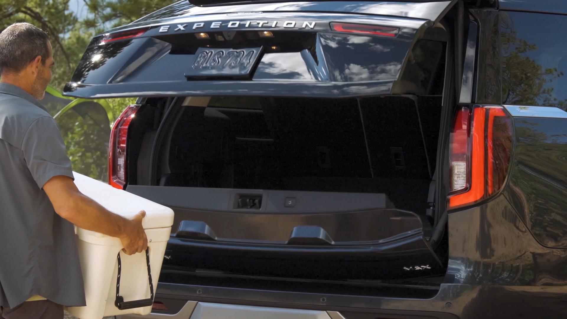 Personne utilisant le portillon divisé Ford avec ouverture à l’approche en option pour charger une glacière dans un VUS Ford Expedition® 2026