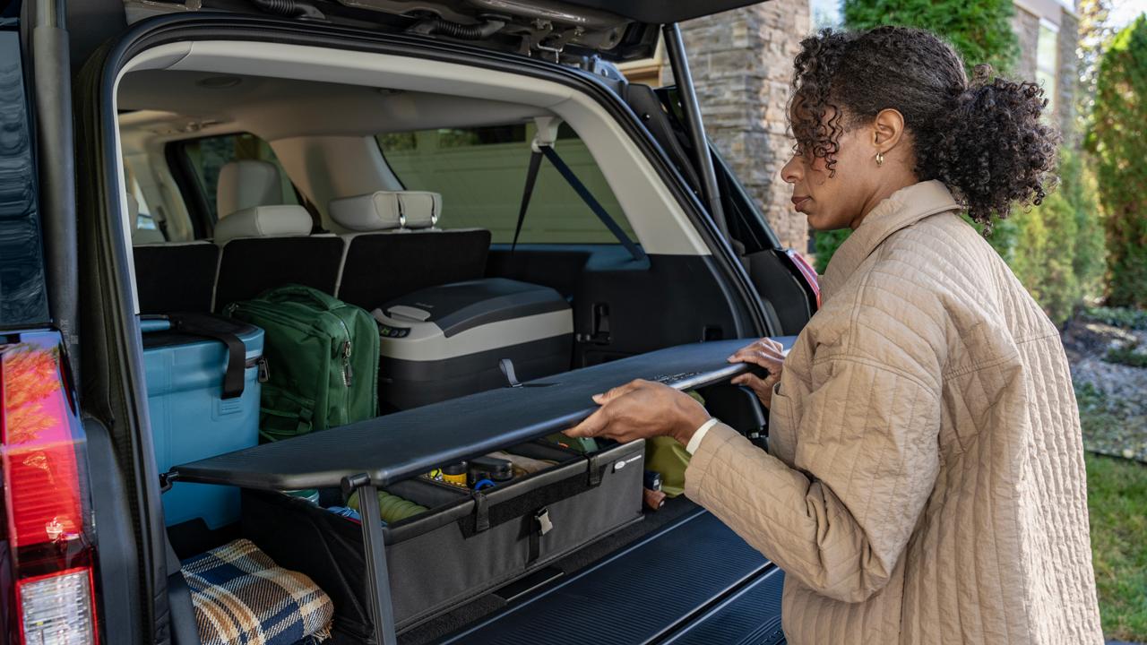 Une personne utilisant l’étagère de l'organisateur de hayon de chargement en option dans un VUS Ford Expedition® 2027  