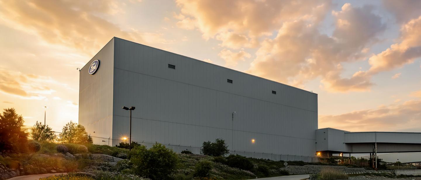 Le complexe d’assemblage Ford d’Oakville, à Oakville, en Ontario, au coucher du soleil, avec le logo Ford visible sur l’extérieur du bâtiment.