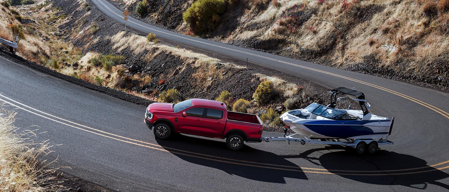 Un camion Ford Ranger® 2026 tirant un hors-bord sur une autoroute sinueuse et montagneuse
