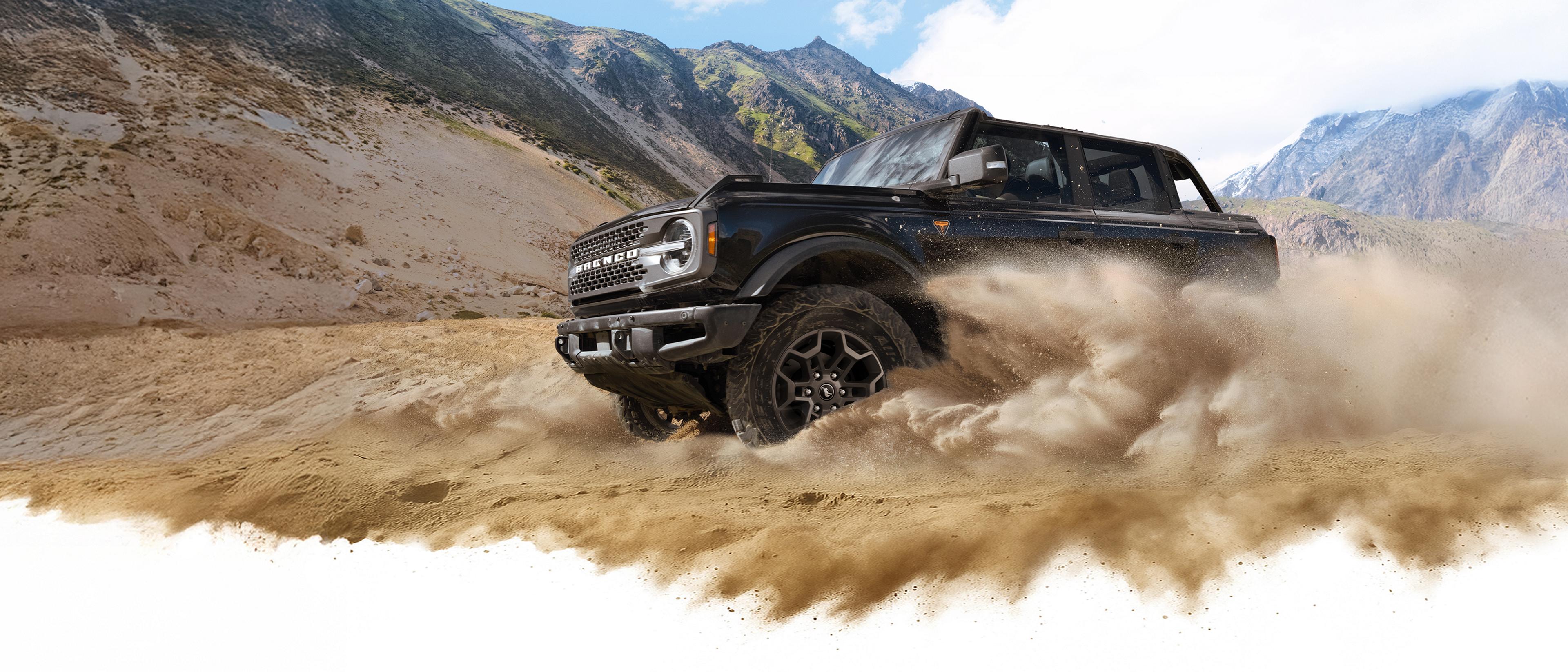 Un VUS Ford Bronco® 2026 soulève la poussière dans une vallée au pied de collines rocheuses