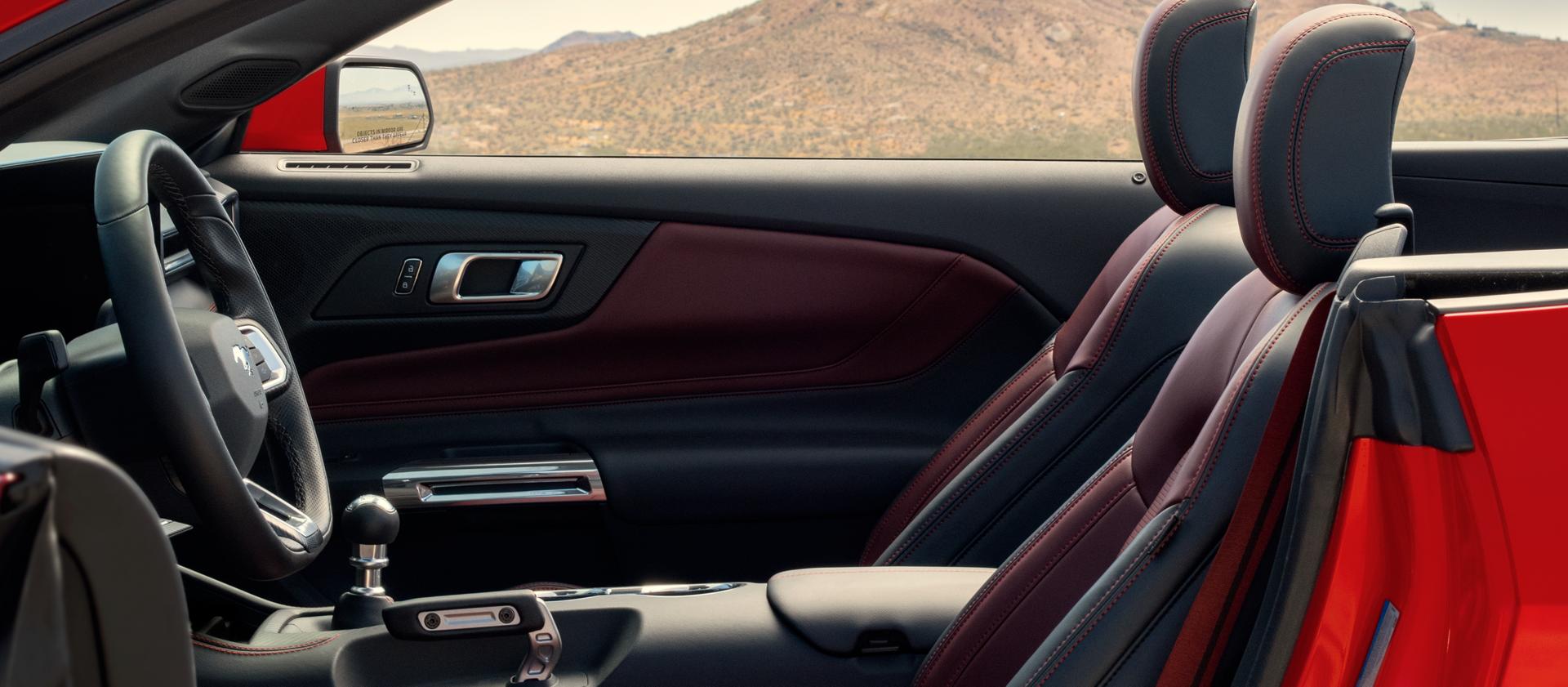 Ford Mustang® 2026 décapotable stationnée avec la portière du côté conducteur ouverte montrant l’intérieur rouge carmin en option