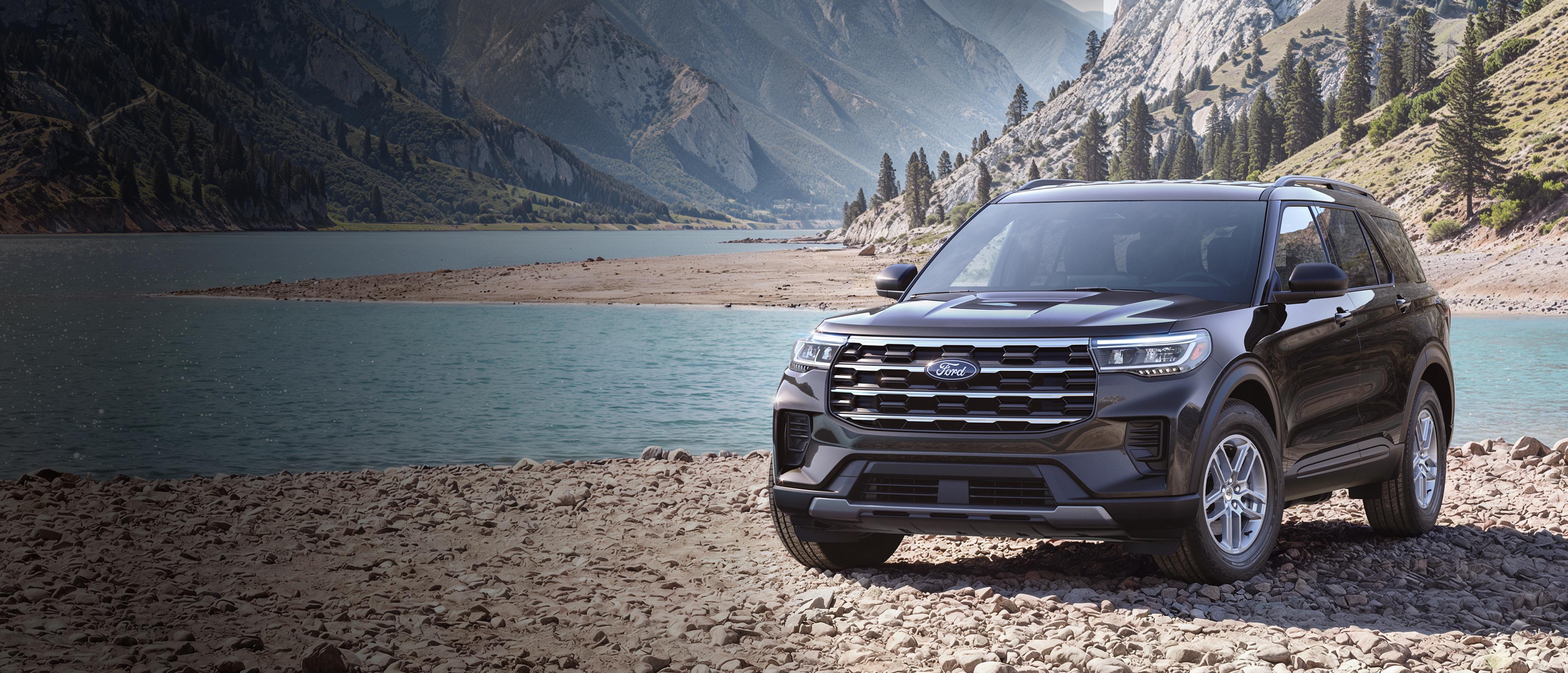 Un modèle Ford Explorer® Active 2027 stationné sur une étendue rocheuse, près d’un lac de montagne