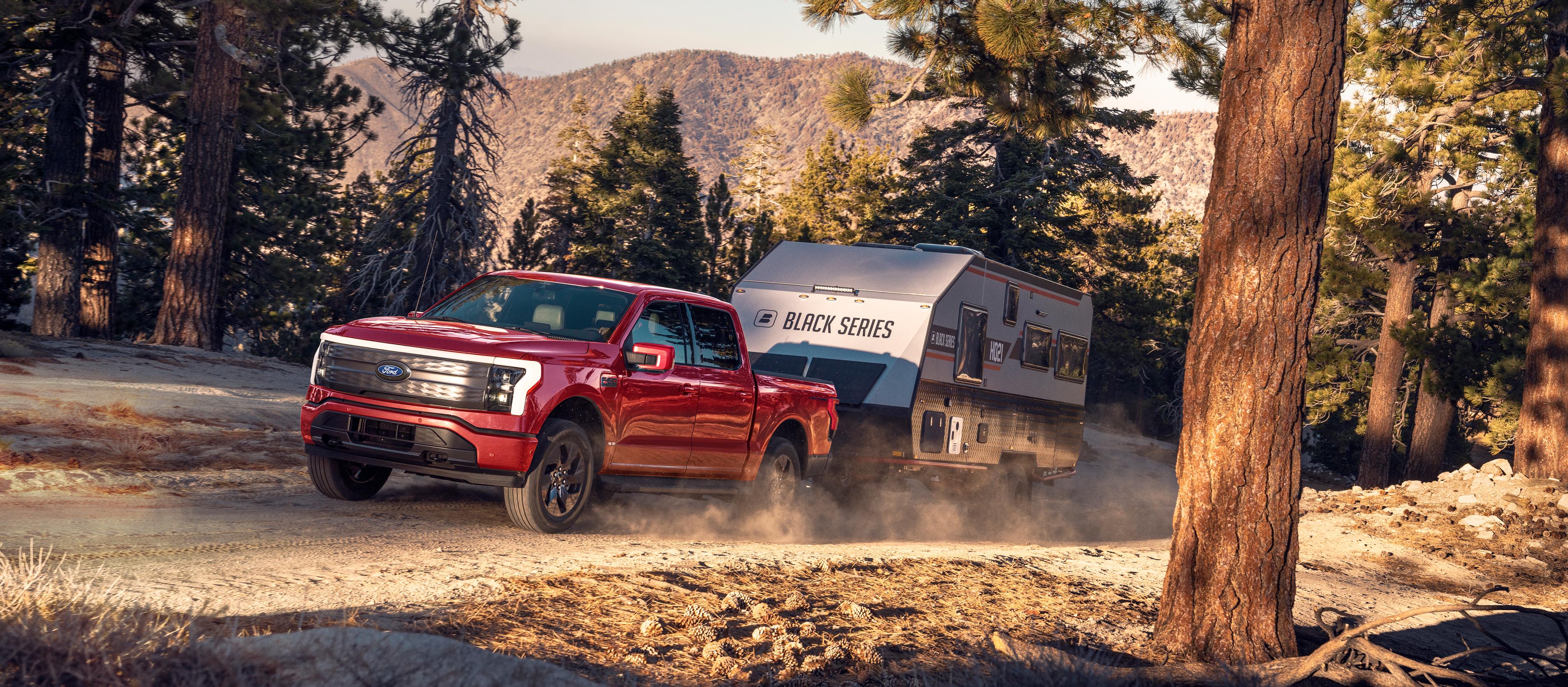 Un Ford F-150® Lightning® 2025 transporte une caravane sur une route de terre dans un endroit pittoresque