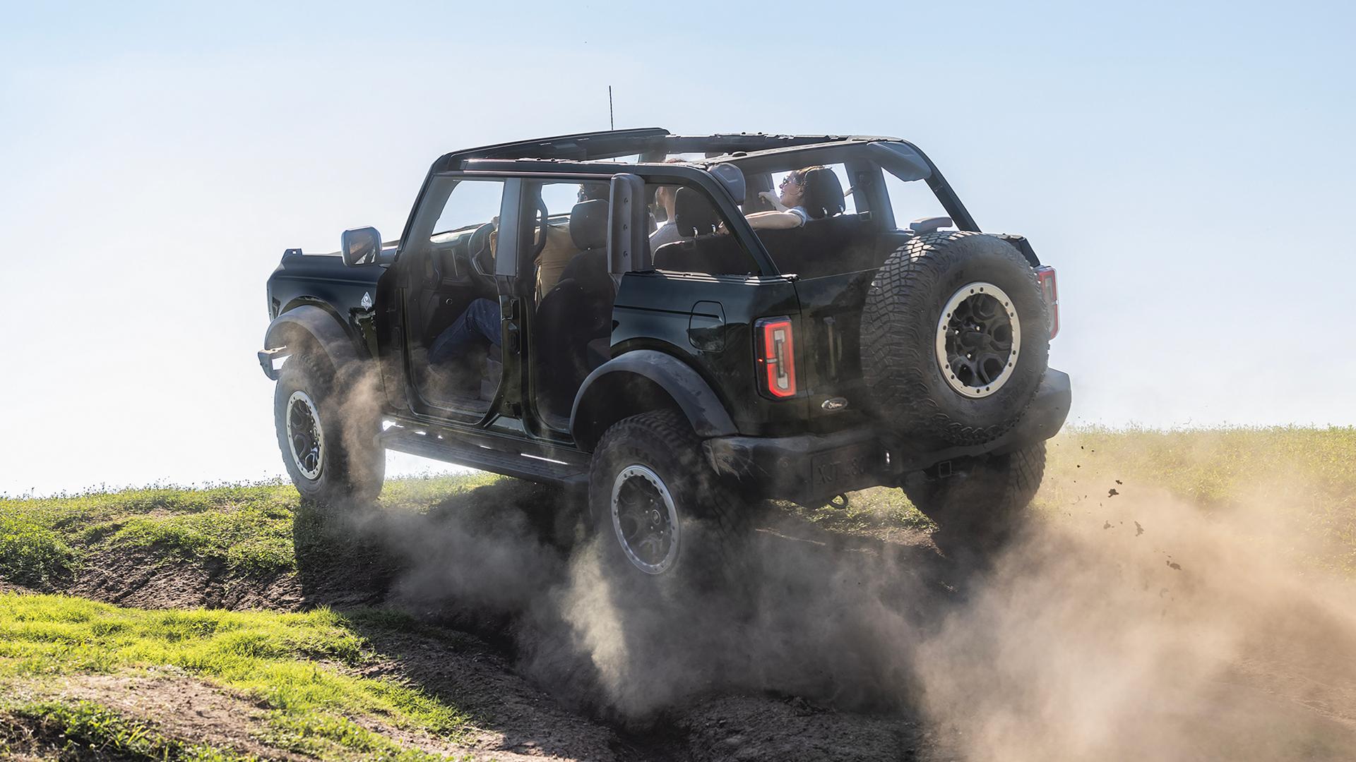 Un VUS Ford Bronco® 2026, dont les portes ont été retirées, gravissant une colline poussiéreuse