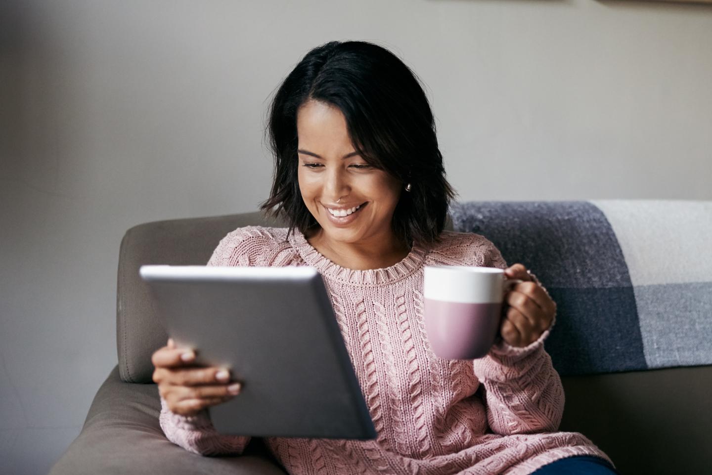 Une personne assise sur un canapé regarde une tablette