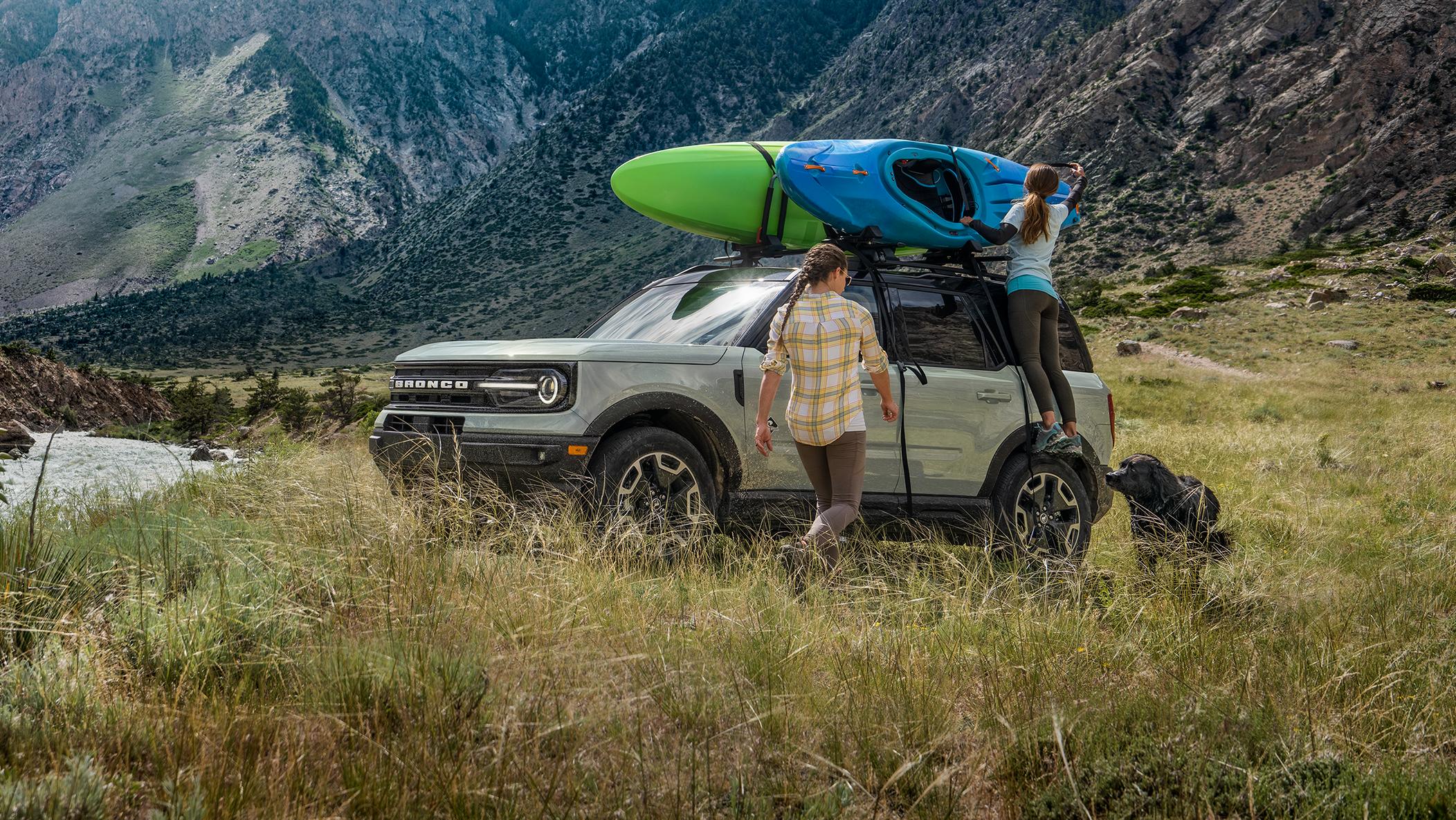 Deux personnes déchargent un Bronco Sport stationné près d’un lac.