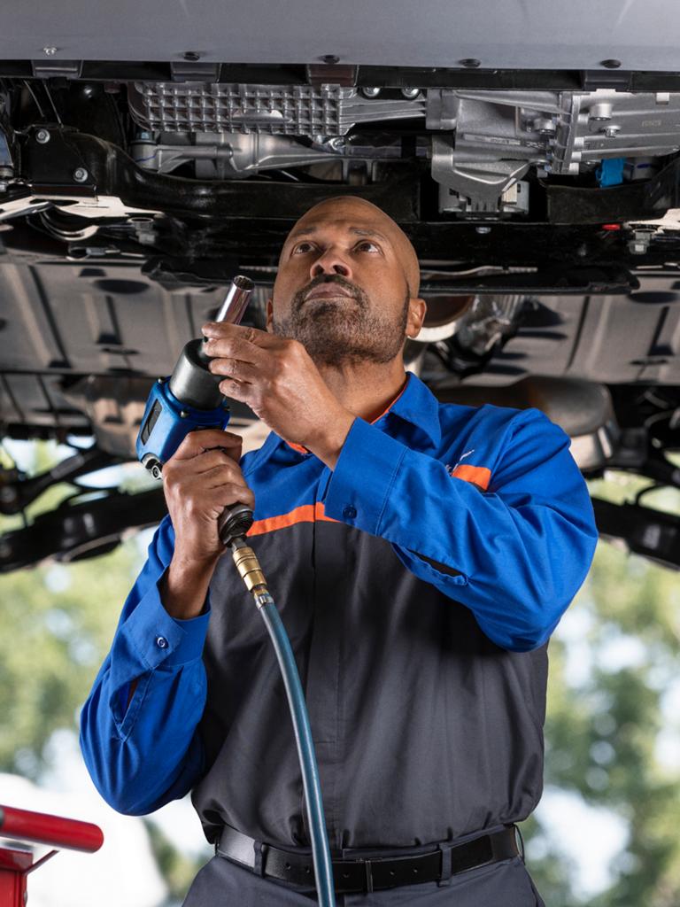 Un garage Service technique Ford avec un homme entretenant un véhicule Ford