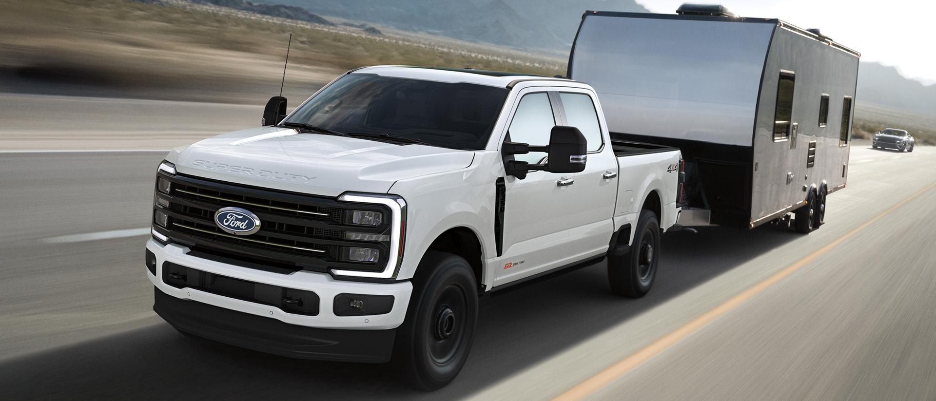 Modèle Ford Super Duty® F-350® Platinum™ 2027 tirant une grande roulotte sur une route pavée.