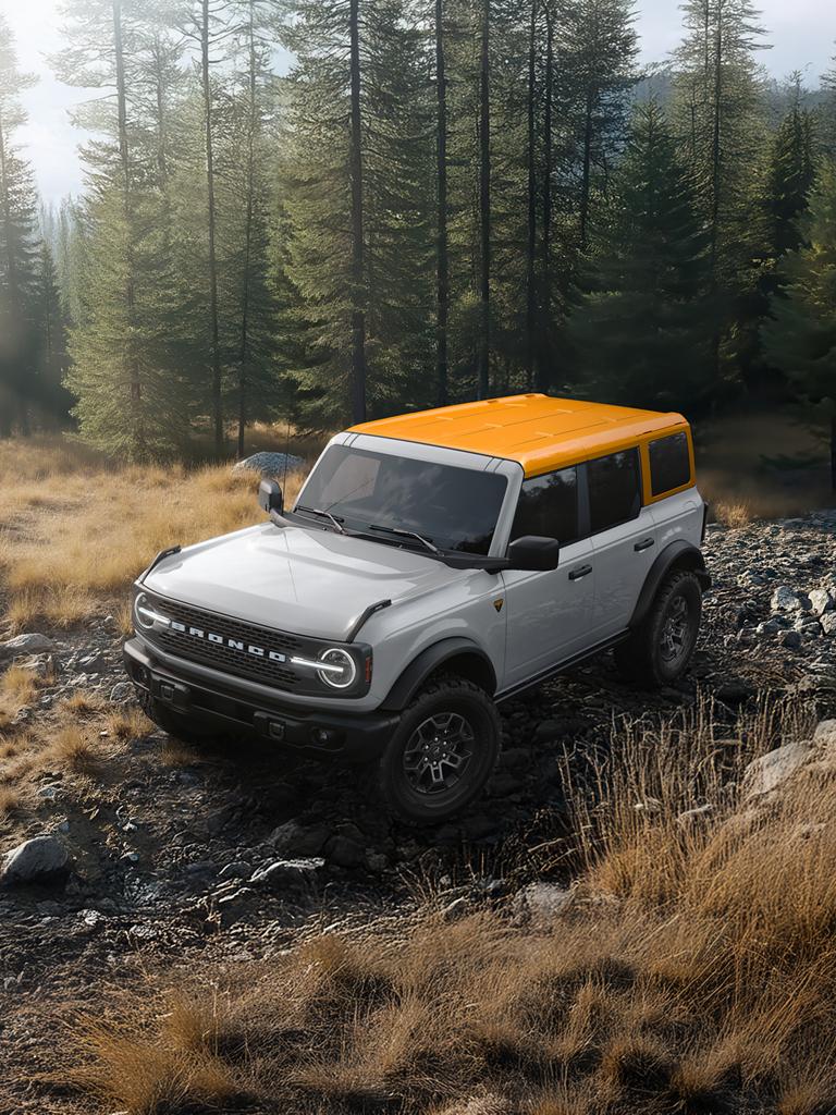 Un VUS Ford Bronco® sur un chemin boueux, avec une carrosserie de couleur sombre et un toit blanc.