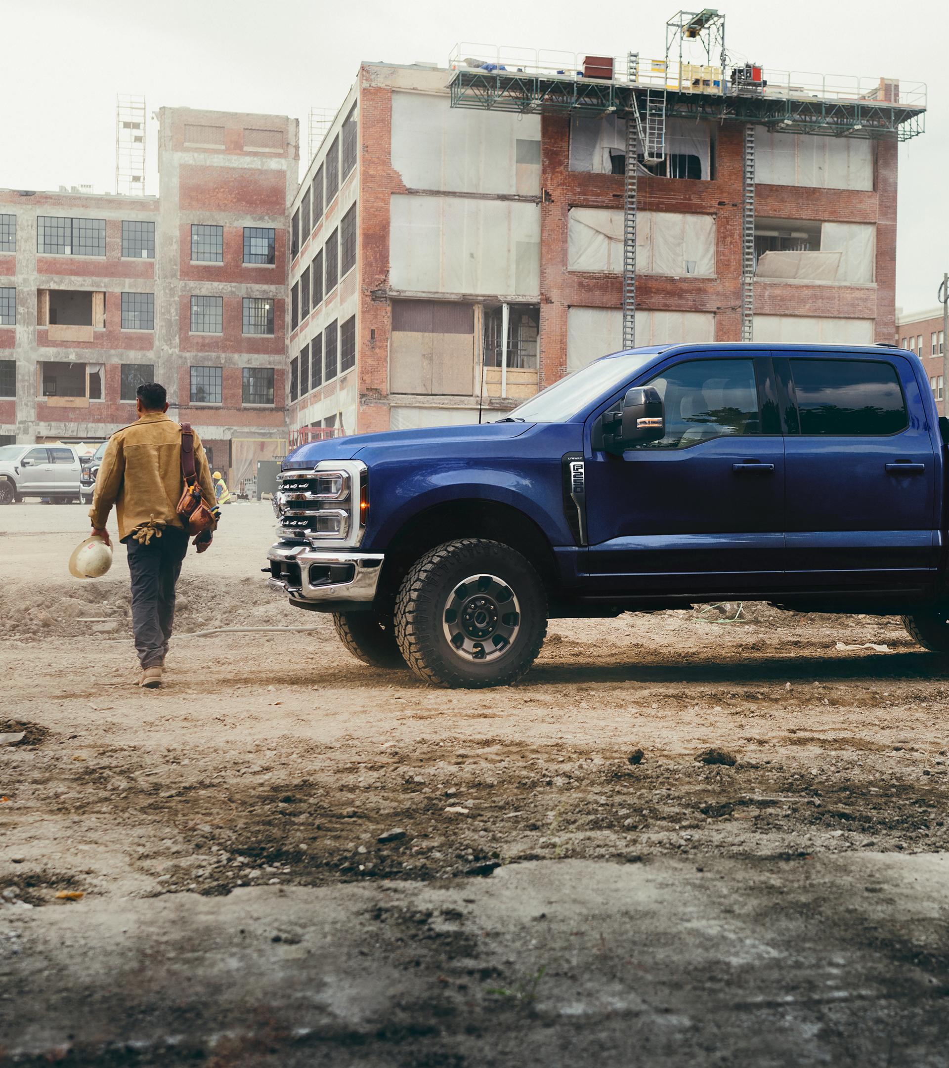 Une personne s’éloignant de son Ford Super Duty® F-250® Lariat 2026 en bleu argon sur un chantier de construction.
