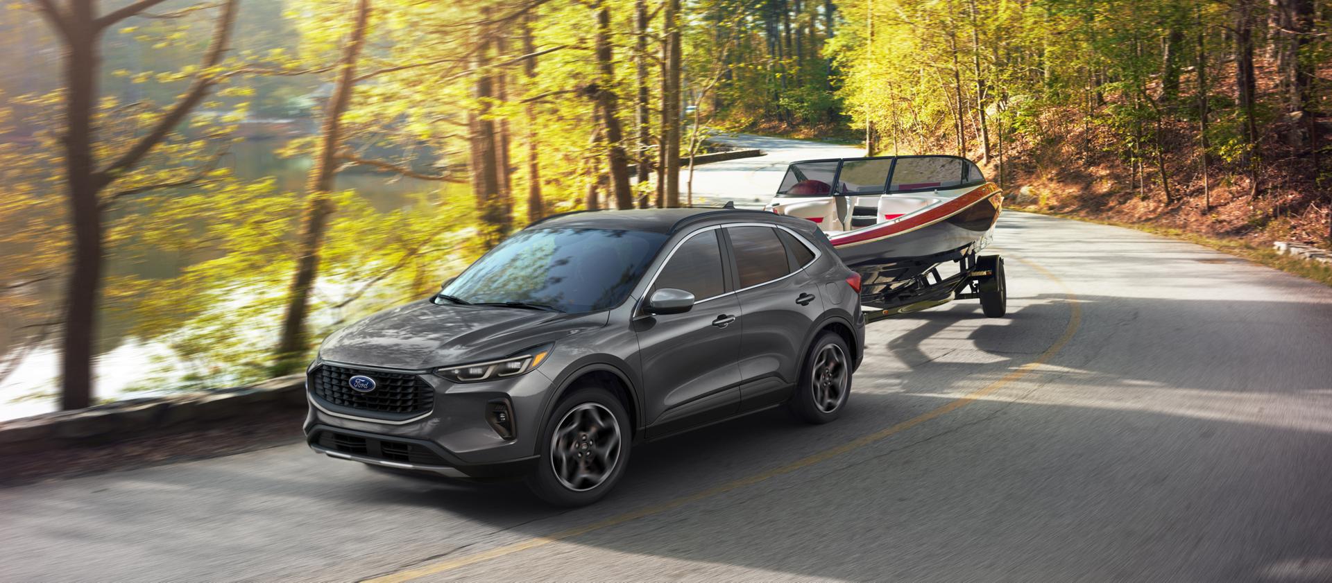 Ford Escape® 2026 avec moteur EcoBoost® de 2,0 L remorquant un bateau sur une route bordée d'arbres