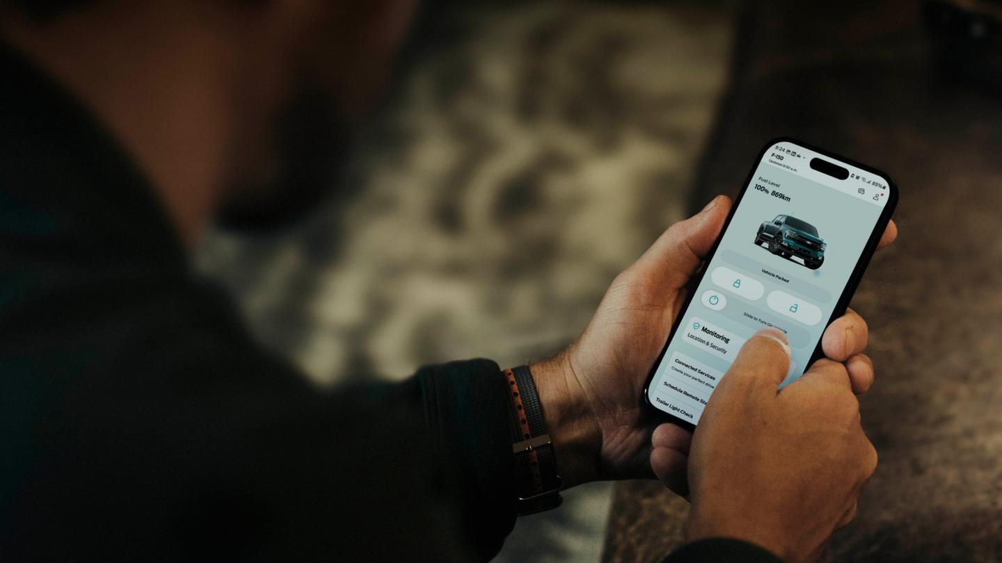 Personne tenant un téléphone intelligent affichant un écran dans l’application Ford.