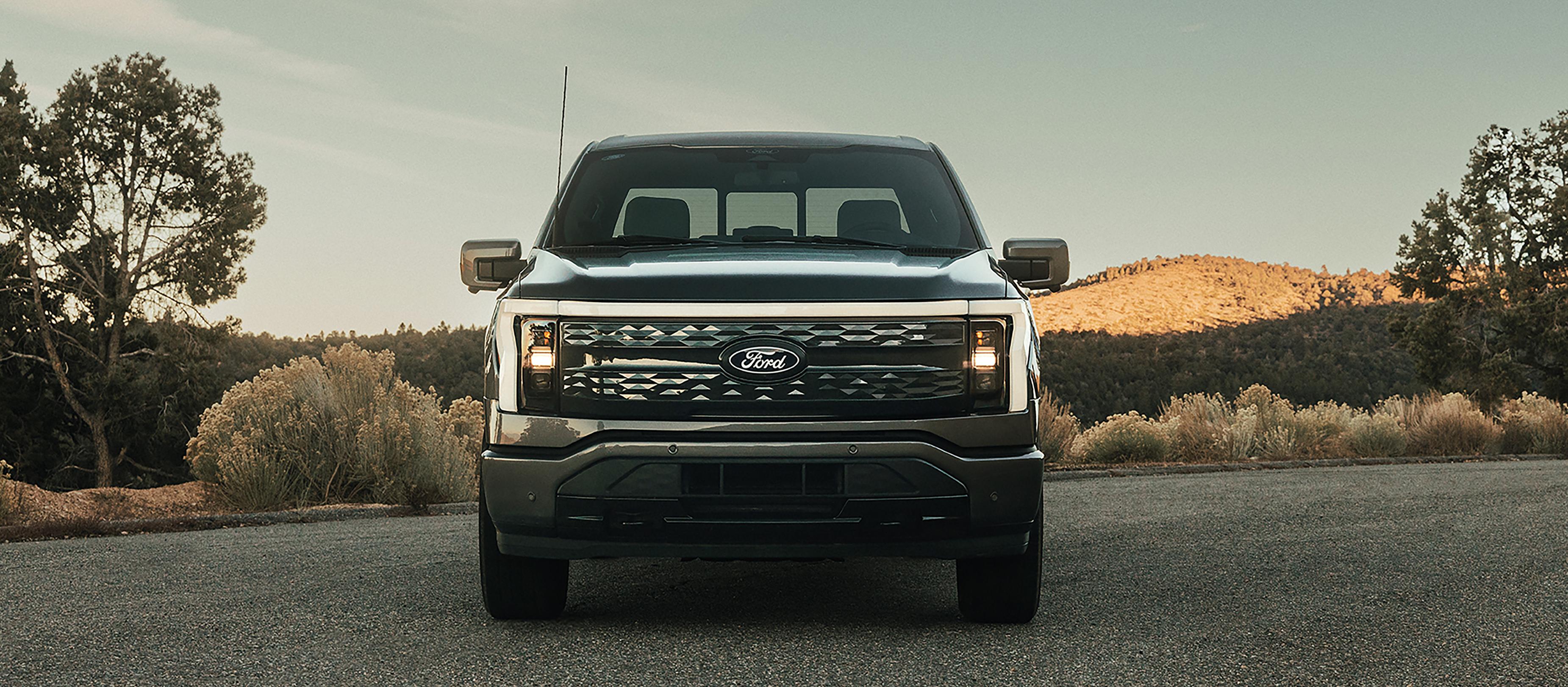 Une vue avant du Ford F-150® Lightning® 2025 stationné au coucher du soleil dans un endroit pittoresque