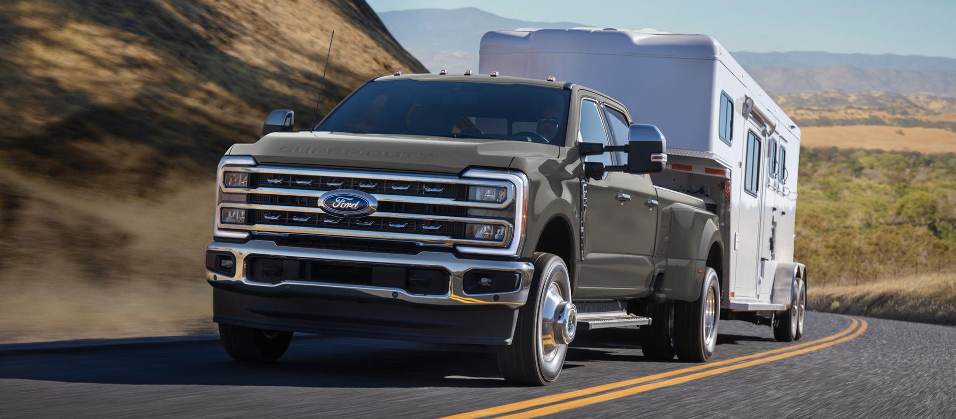 Modèle Ford Super Duty® F-350® Lariat® 2026 en gris marais tirant une remorque sur une route pavée