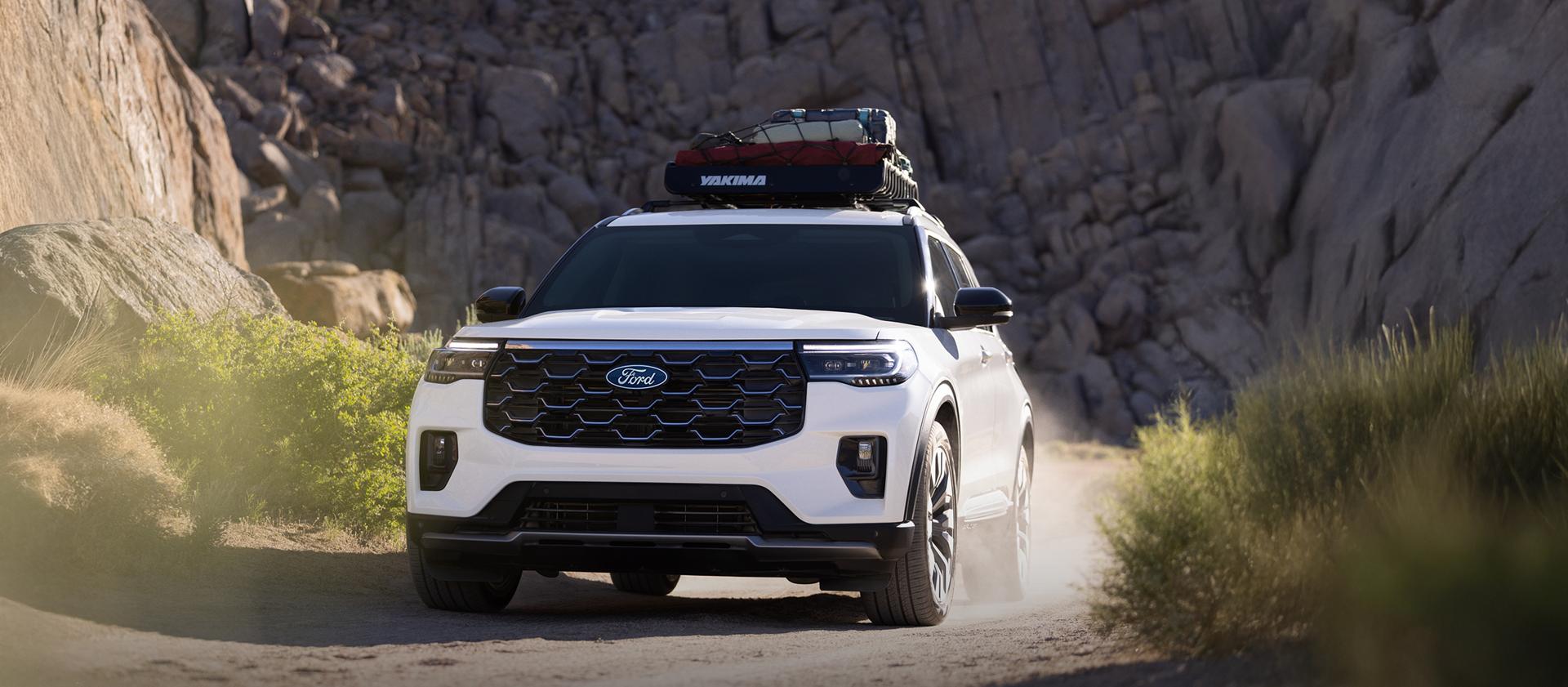Un VUS Ford Explorer® Platinum™ 2027 avec des bagages sur le toit, soulevant de la poussière alors qu’il roule dans un canyon poussiéreux
