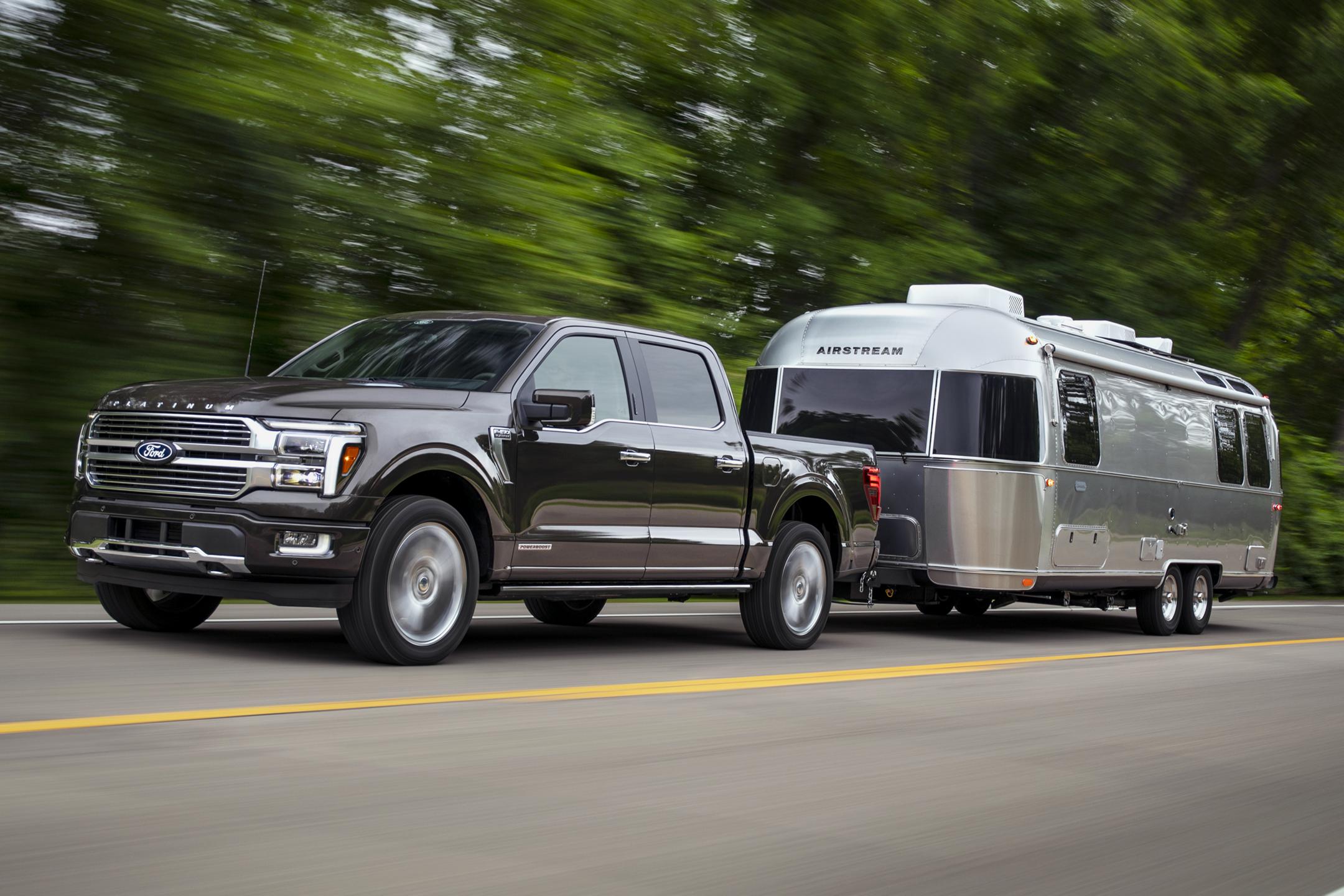 Un F-150 remorque un véhicule récréatif sur une route à deux voies.