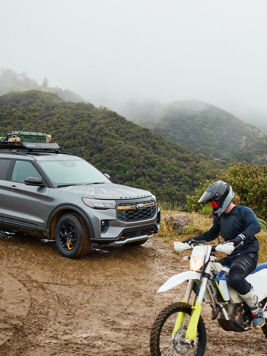 Une personne roule à moto tout-terrain près d'un Ford Explorer