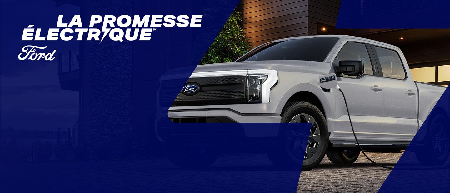 La promesse électrique Ford. Un F-150 Lightning stationné dans l'allée d'une maison et branché à un chargeur domestique.
