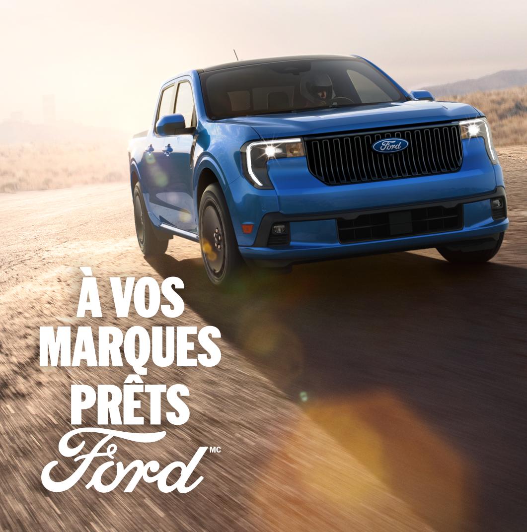 Modèle Ford Maverick Lobo™ 2026 en bleu vélocité métallisé roulant sur un circuit fermé avec un paysage urbain en arrière-plan
