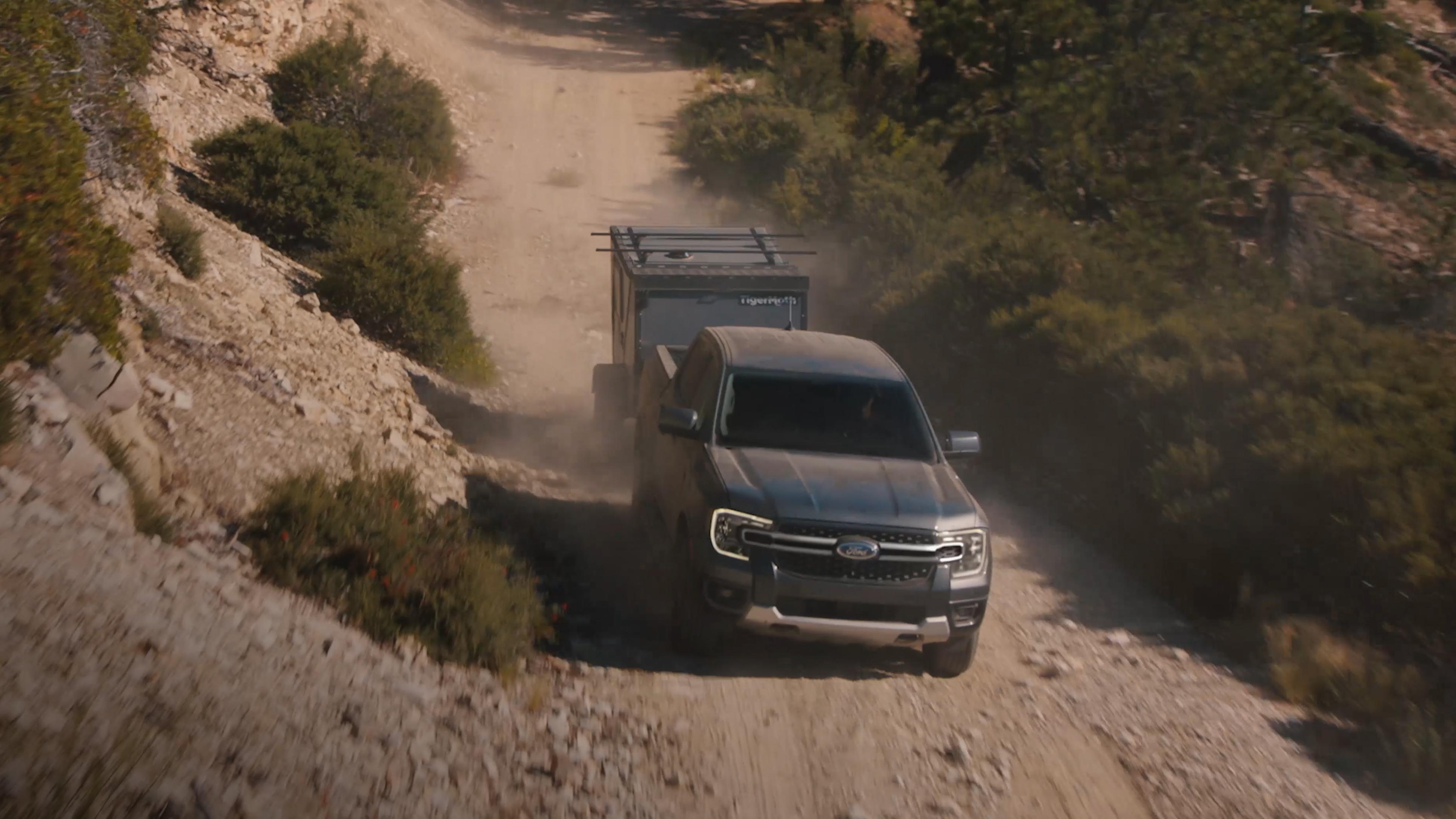 Camion Ford Ranger® 2026 tirant une remorque sur une route de terre dans les montagnes