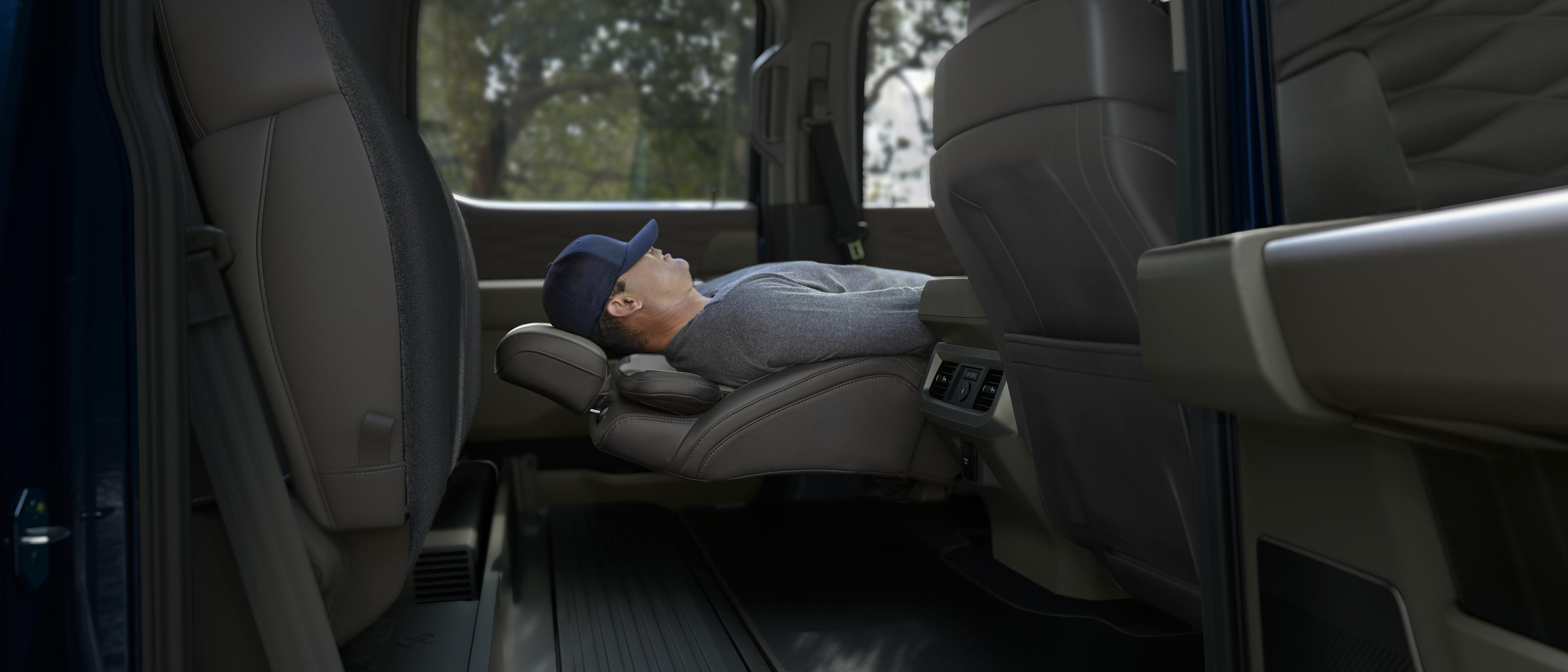 Une personne dort en utilisant les sièges avant à inclinaison maximale dans son camion Ford Super Duty® 2026