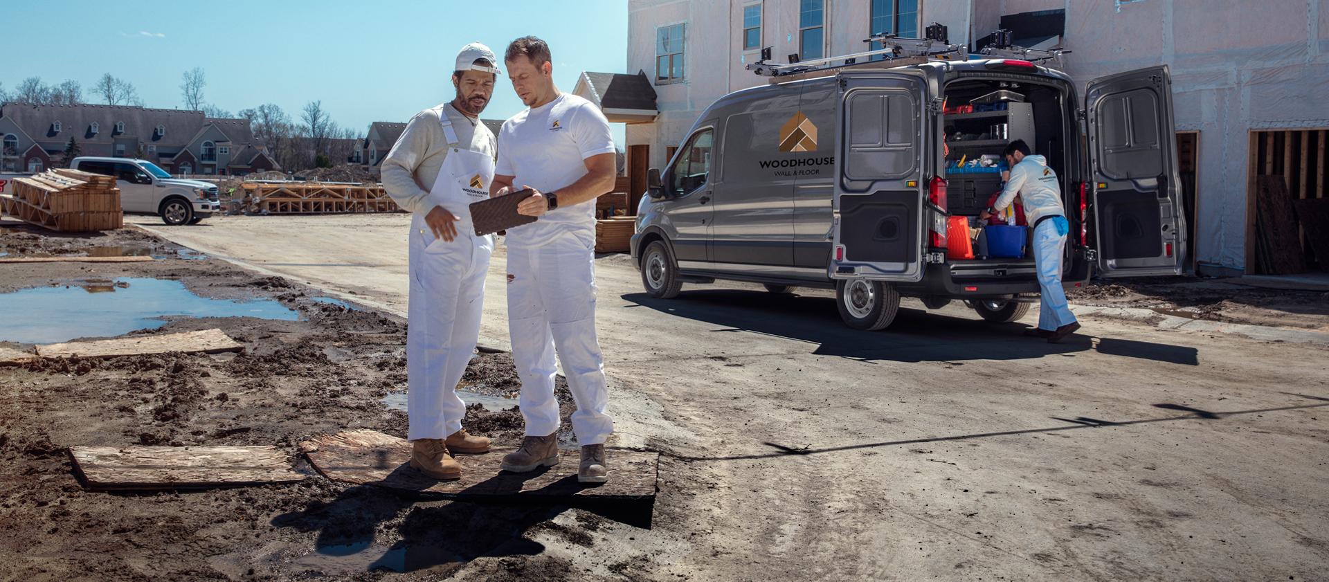 Deux peintres consultent une tablette à côté de leur fourgonnette Ford Transit® 2027 sur un chantier de construction