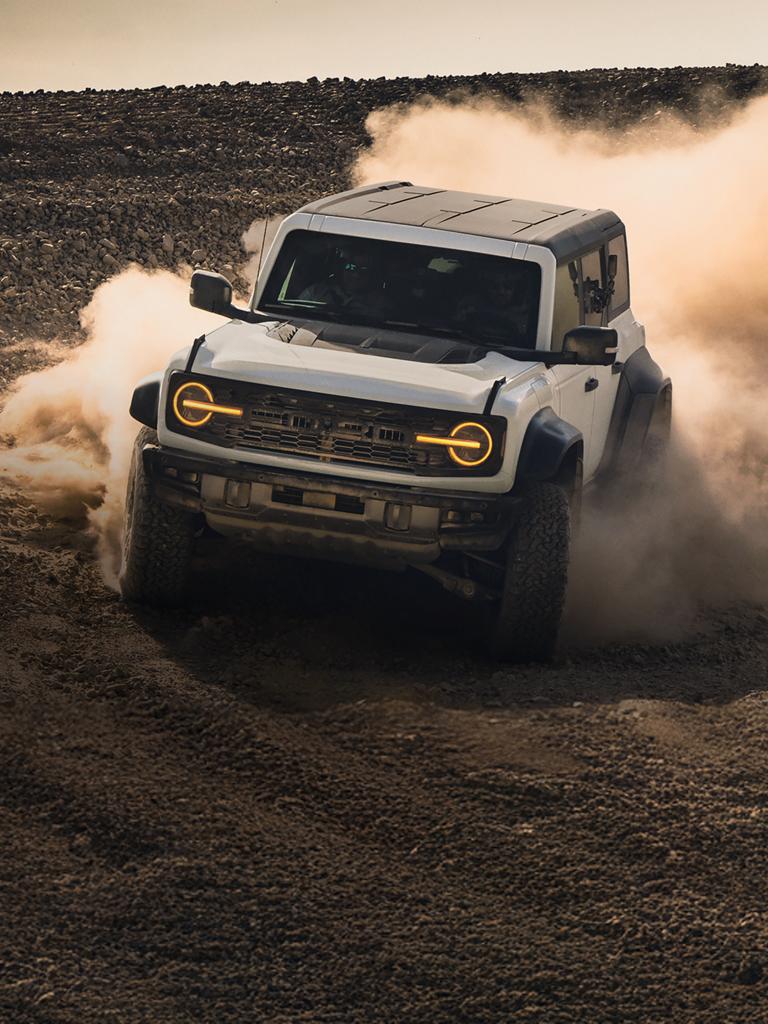 Un VUS Ford Bronco® 2026 rugissant à travers un champ poussiéreux