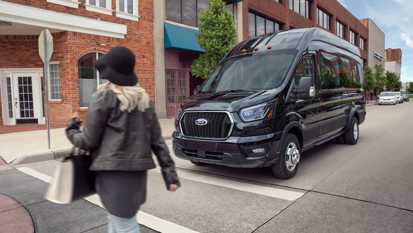Une fourgonnette Ford Transit® 2026 arrêtée à un panneau d’arrêt, en attente qu’un piéton traverse