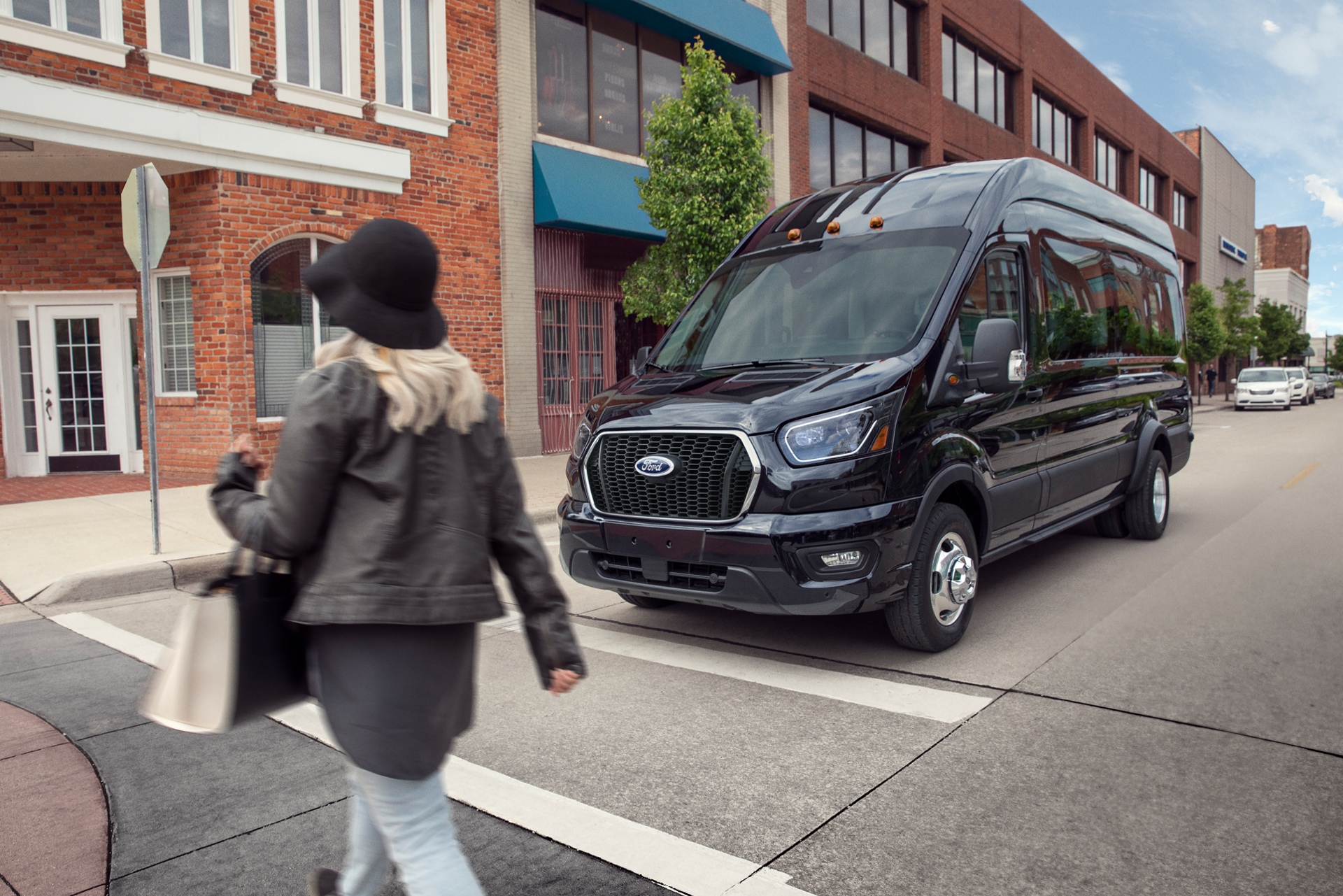 Une fourgonnette Ford Transit® 2026 arrêtée à un panneau d’arrêt, en attente qu’un piéton traverse