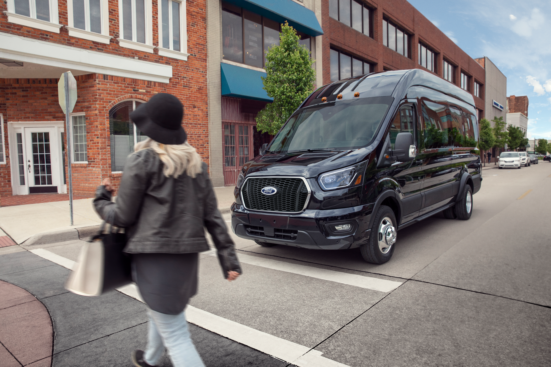 Une fourgonnette Ford Transit® 2026 arrêtée à un panneau d’arrêt, en attente qu’un piéton traverse