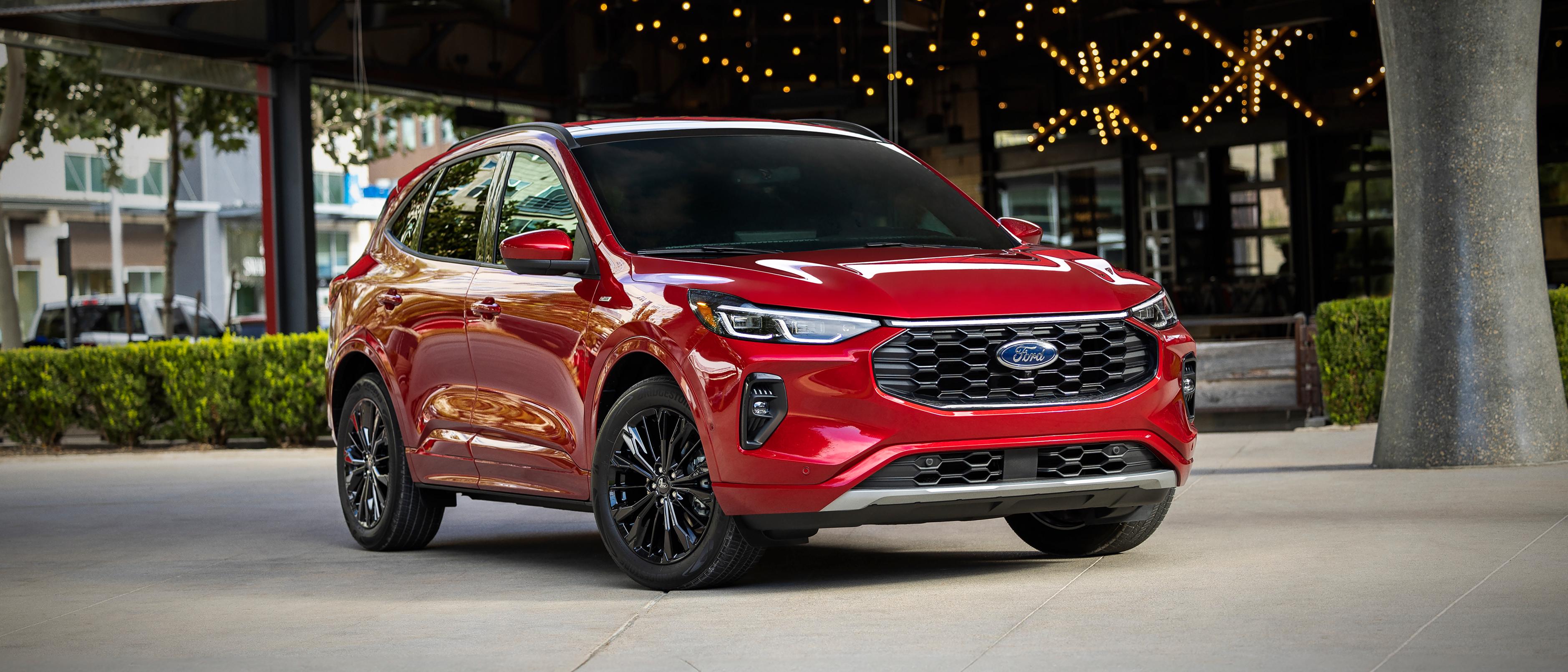 VUS Ford Escape® 2026 en rouge rapide stationné devant un bâtiment décoré de guirlandes lumineuses