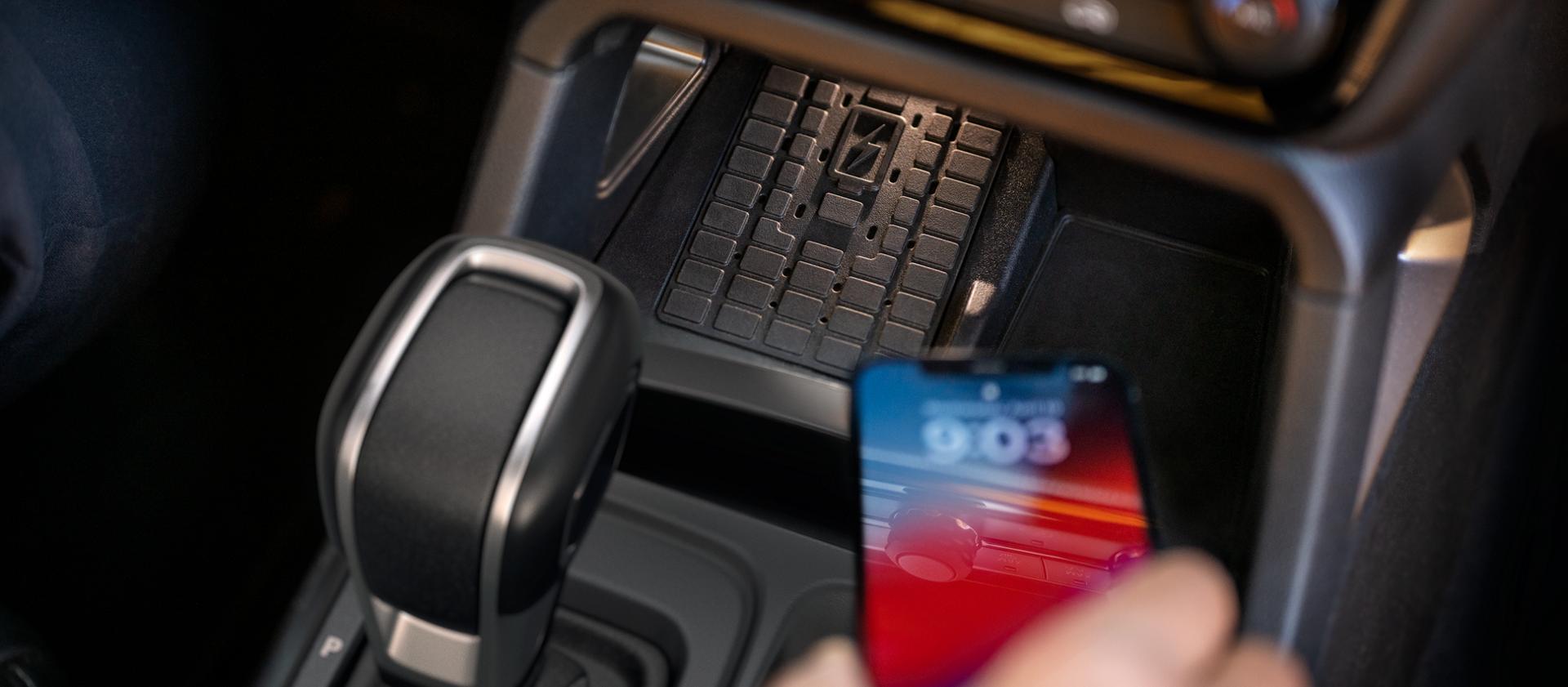Gros plan d’une personne plaçant un téléphone sur le chargeur sans fil du Ford Ranger® 2025