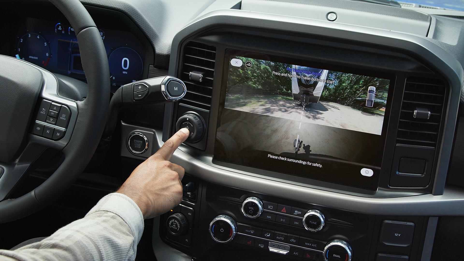 Une personne active le Pro Trailer Hitch Assist™ à l’aide du bouton Pro Trailer à l’intérieur d’un camion Ford F-150® 2025