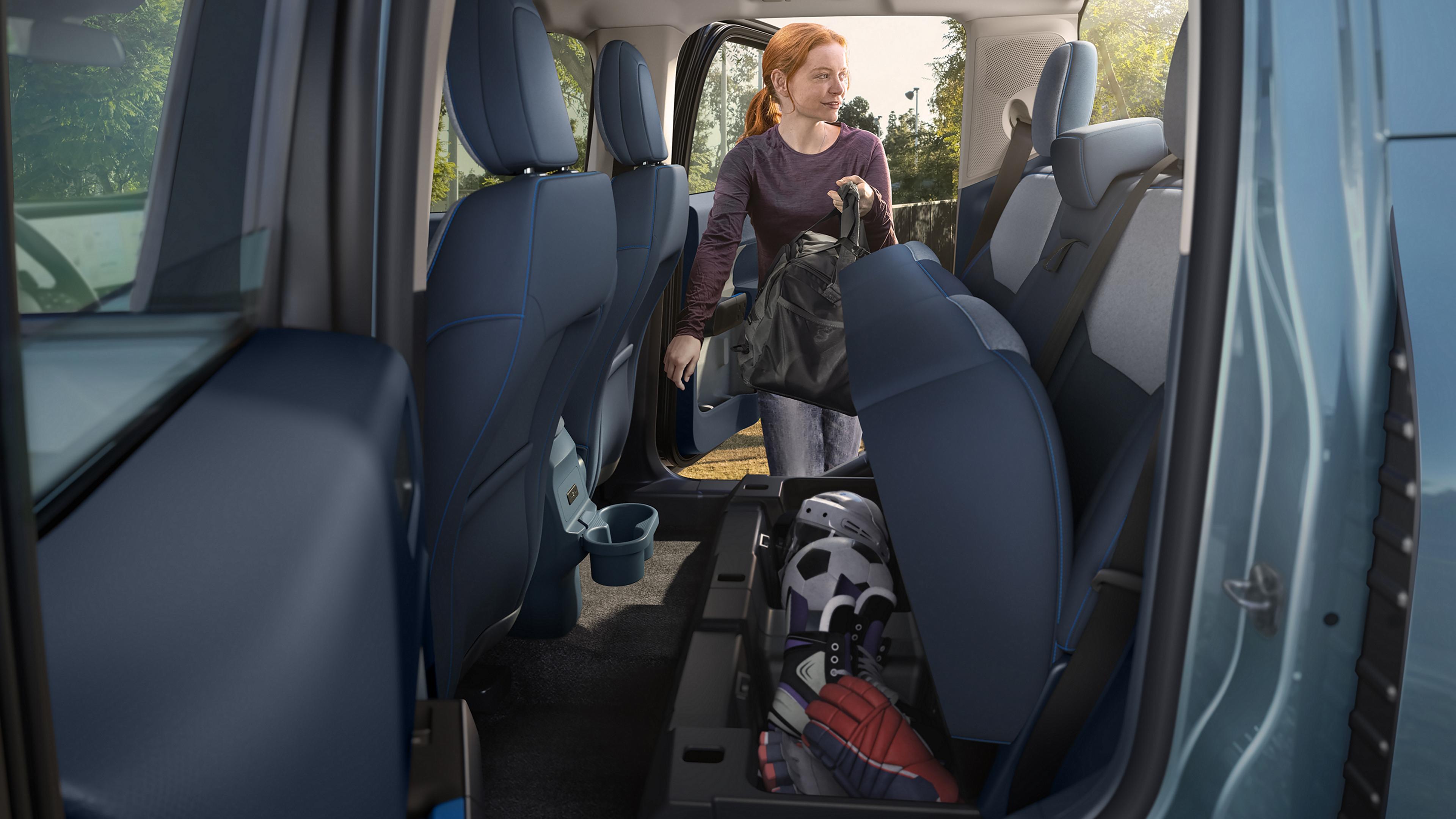 Une femme rangeant un sac sous le siège d’une camionnette Ford Maverick®