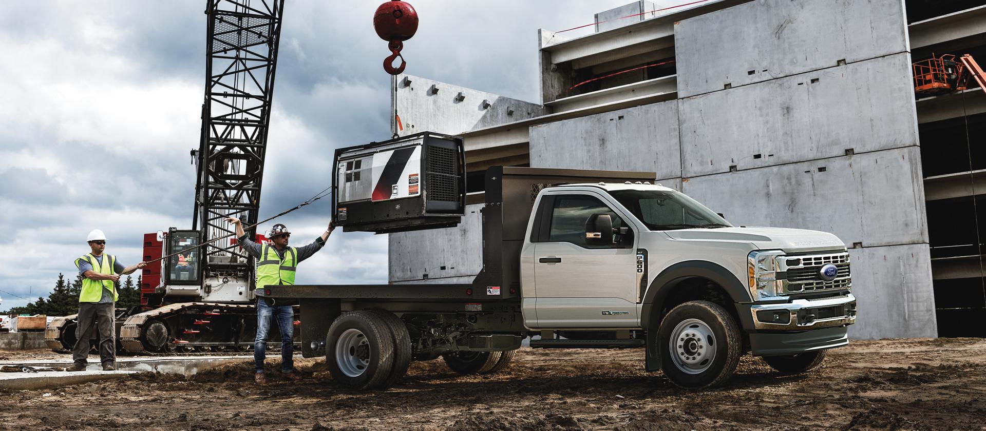 Un Ford Super Duty® à châssis-cabine 2026 stationné sur un chantier de construction alors qu’un objet est chargé sur la plateforme