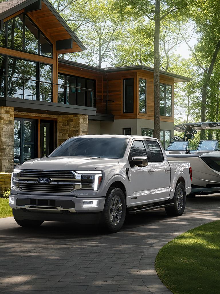 Modèle Ford F-150® Platinum® 2026 avec ensemble Platinum satin fixé à une remorque de bateau stationnée devant une maison