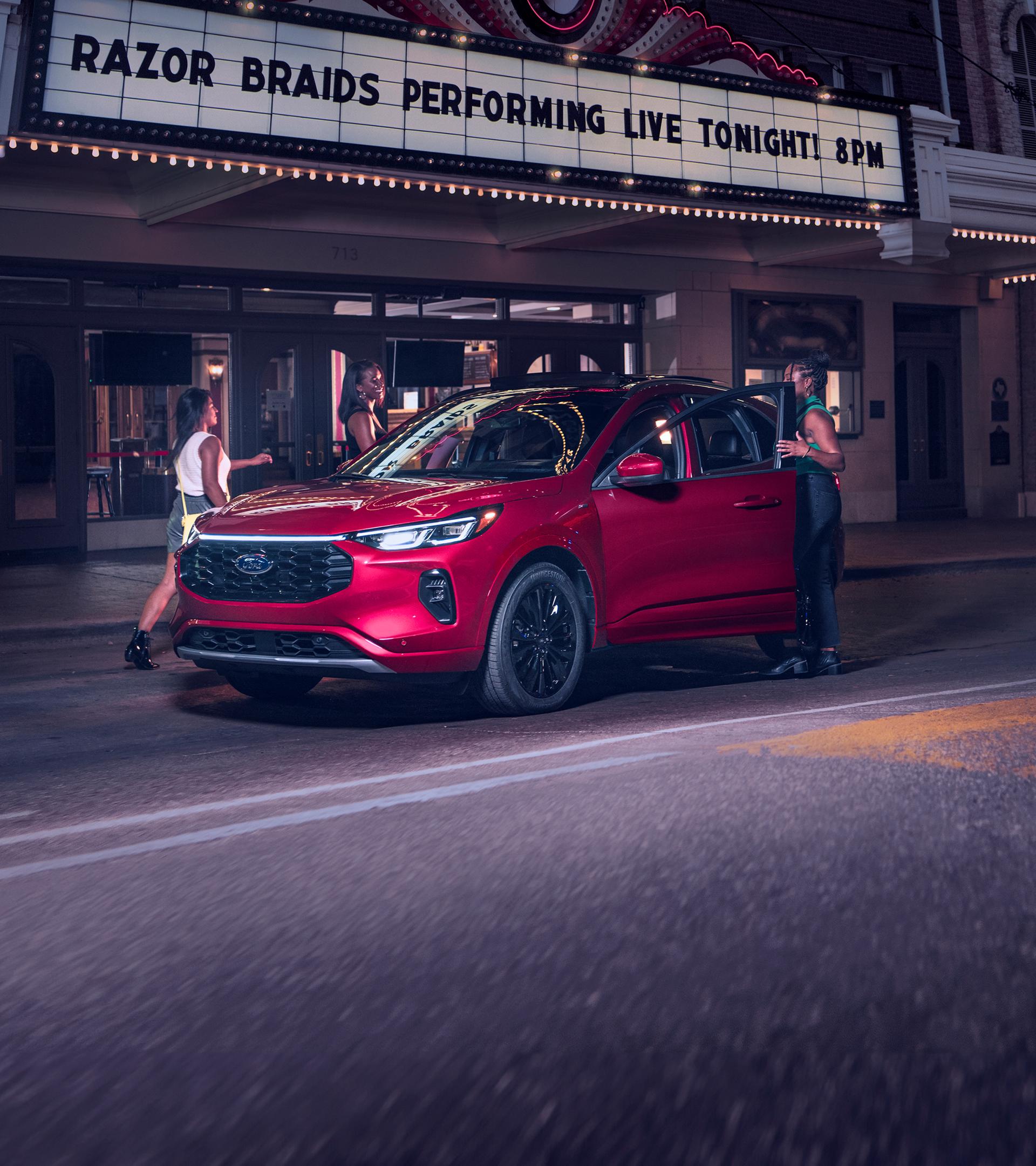 Un Ford Escape 2026 de couleur rouge garé devant un théâtre